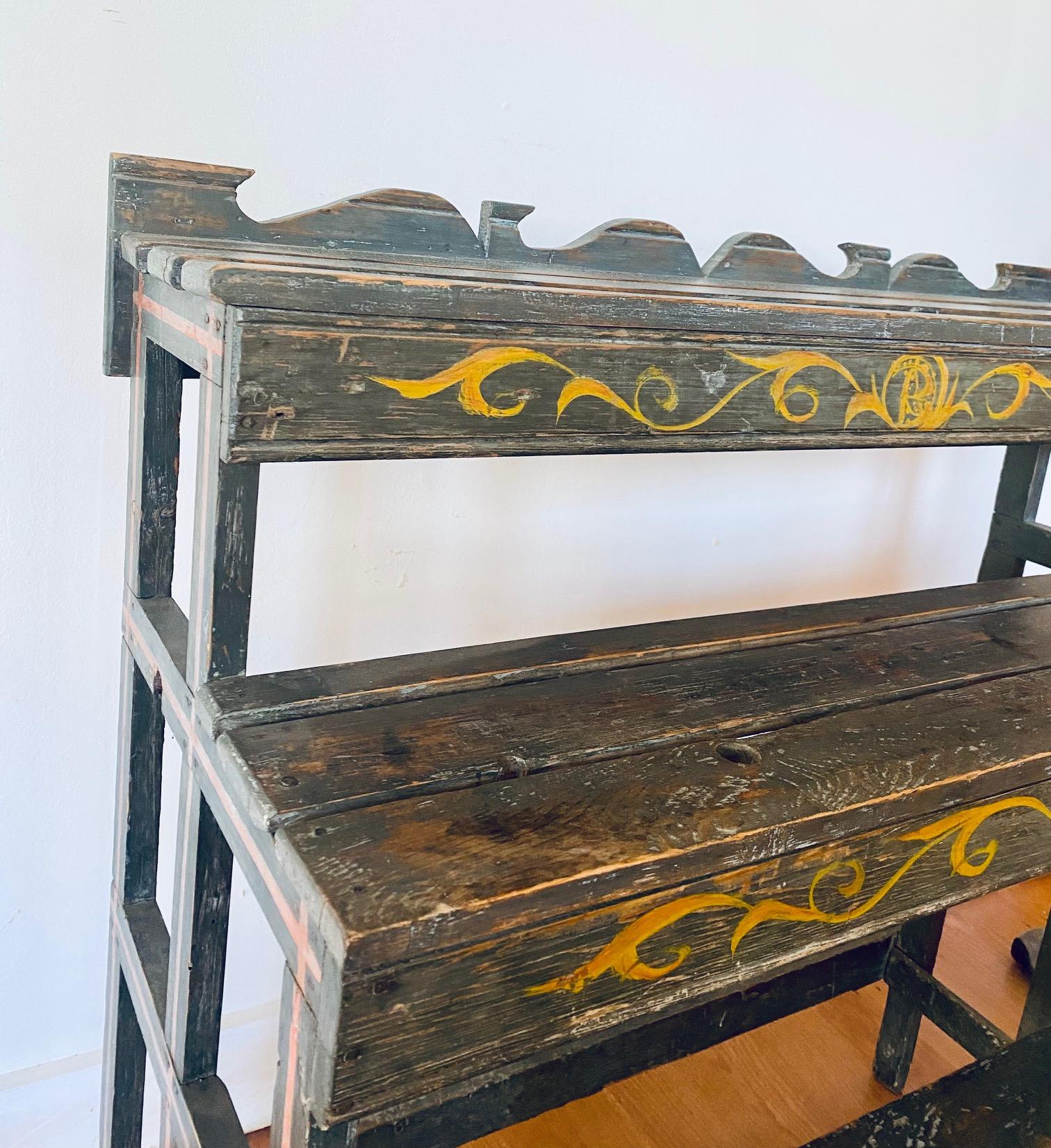 Antique Quebec paint decorated plant stand or bucket bench, circa 1890, pine slat construction with three shelves, fluted backsplash and apron, and delightful yellow scroll decoration on blue ground. From the collection of Peter Baker, author of