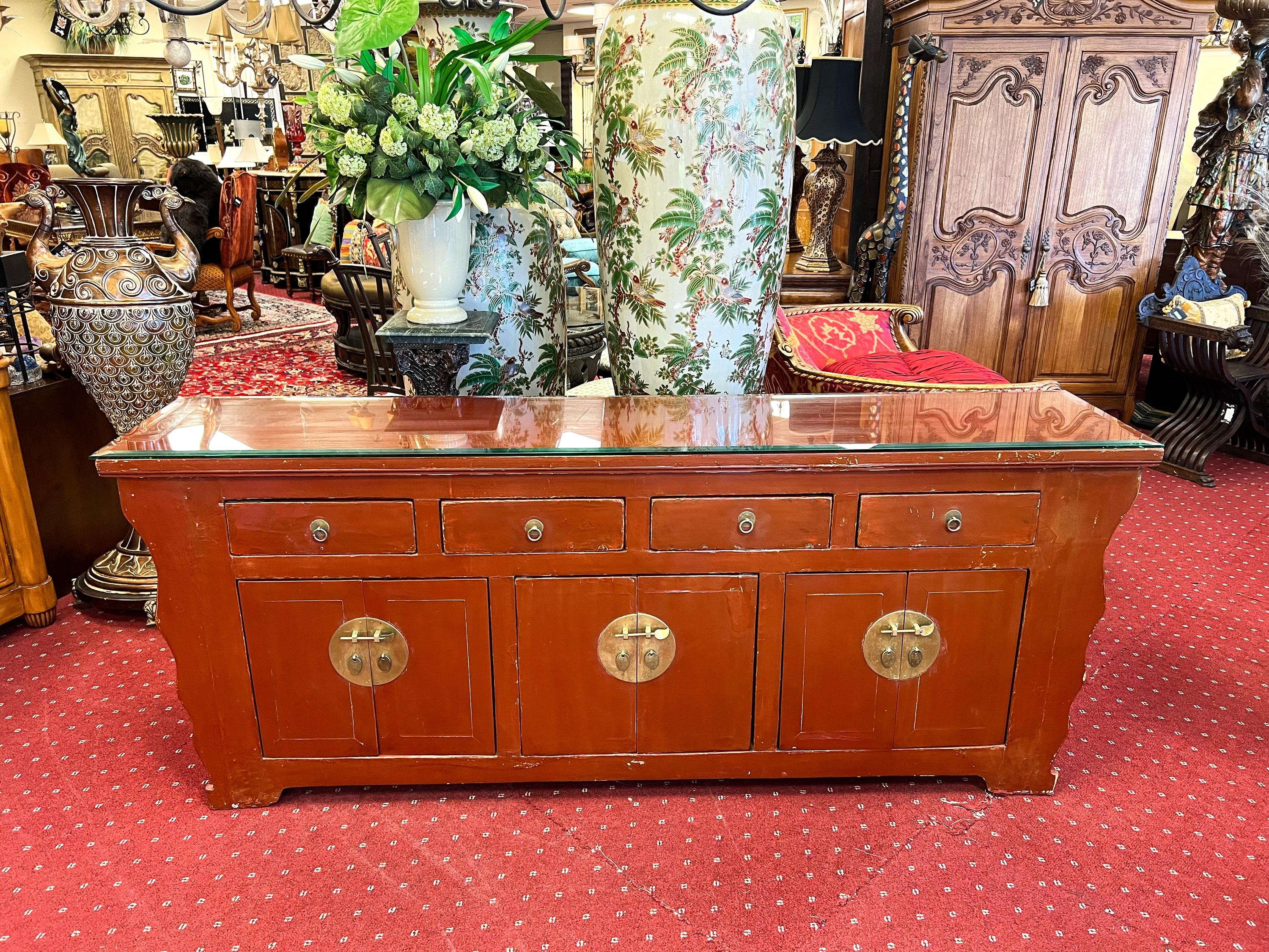 An Asian red lacquered credenza/sideboard that embodies elegance and functionality on a grand scale. This stunning piece of furniture is designed to make a statement in any space.

The red lacquer finish exudes a sense of richness and vibrancy,