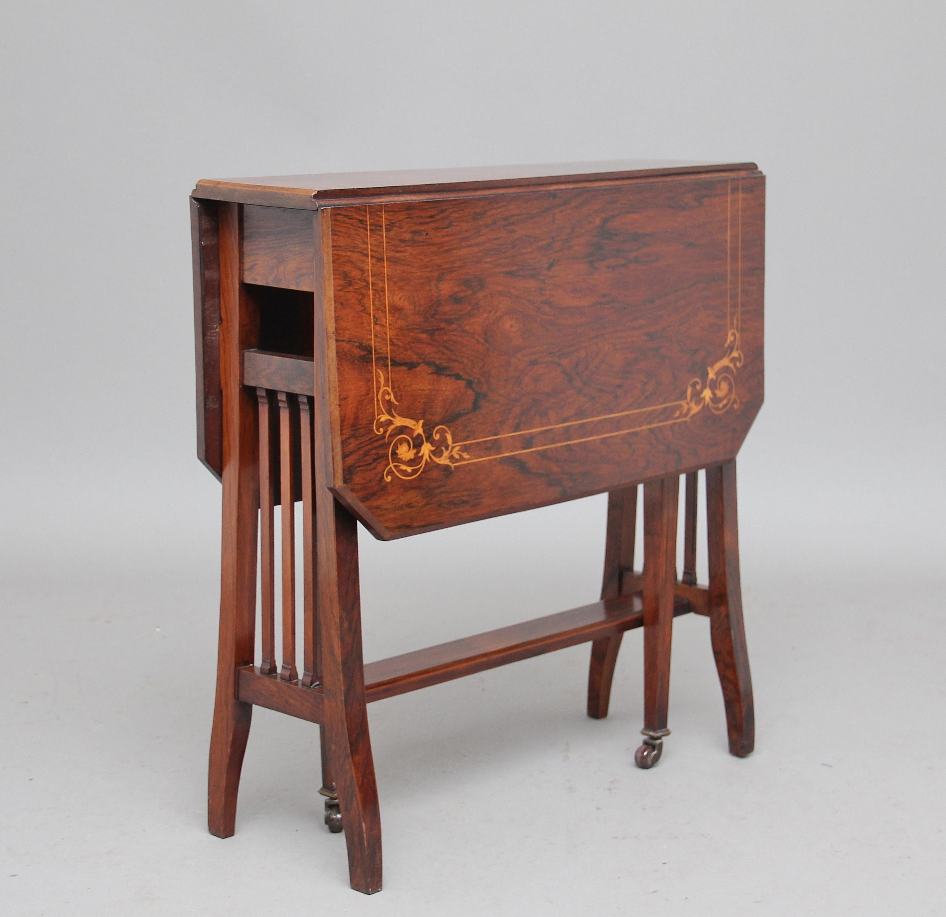 Late 19th Century rosewood Sutherland table, the drop leaf top having fine floral inlay decoration, shaped end supports united with a central stretcher, with two pull out square tapering legs terminating on brass caps and castors which hold the drop