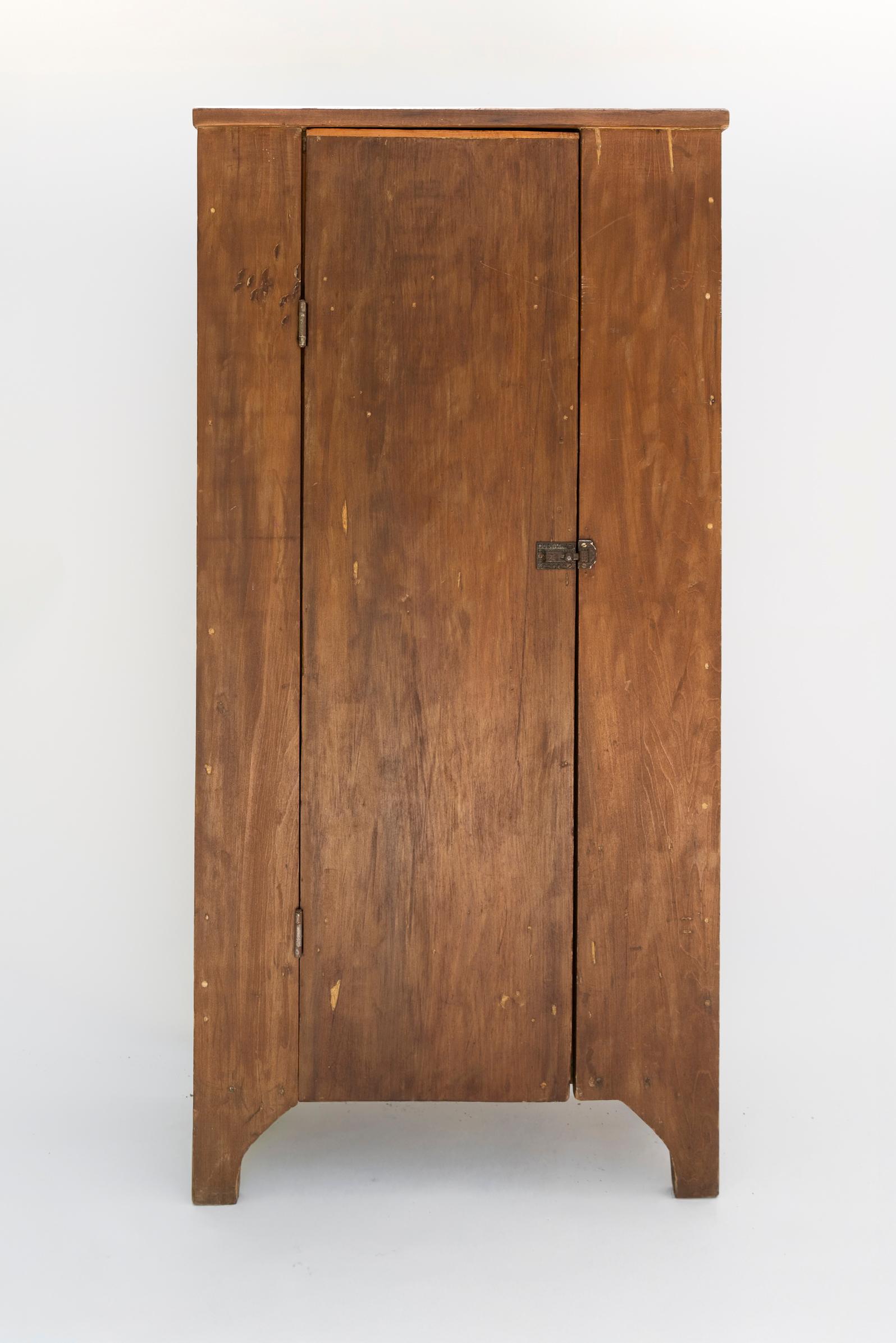 A charming example of utilitarian American craftsmanship, this late 19th-century rustic cabinet is constructed from solid pine and features a timeworn patina that speaks to its enduring character. The tall, narrow form is accentuated a a single