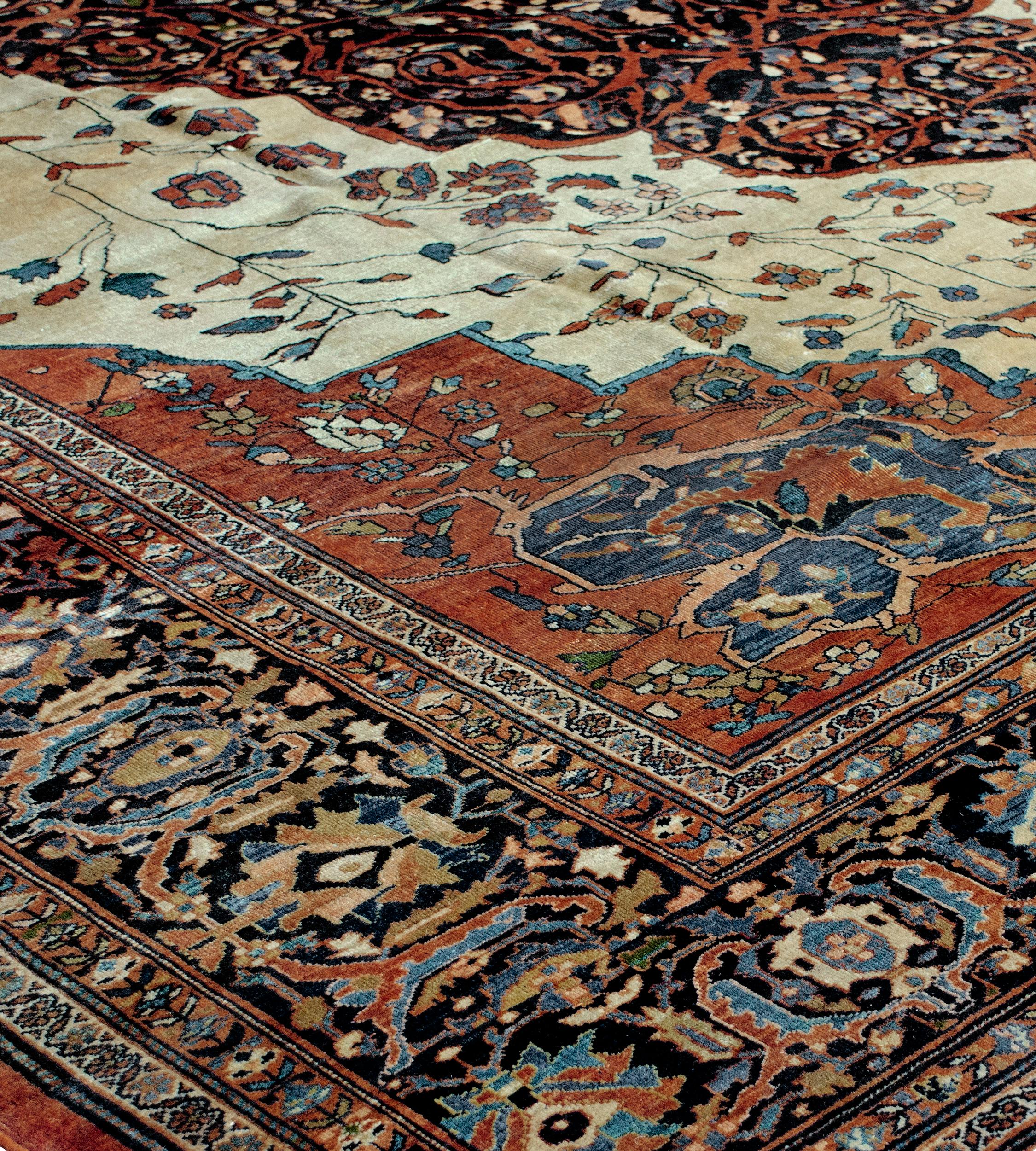 Ce tapis persan Sarouk Fereghan tissé à la main présente un accueillant champ ivoire de vignes florales clairsemées et sinueuses, entourant un royal médaillon losangé en arabesque indigo de vignes florales denses et enroulées, avec des écoinçons
