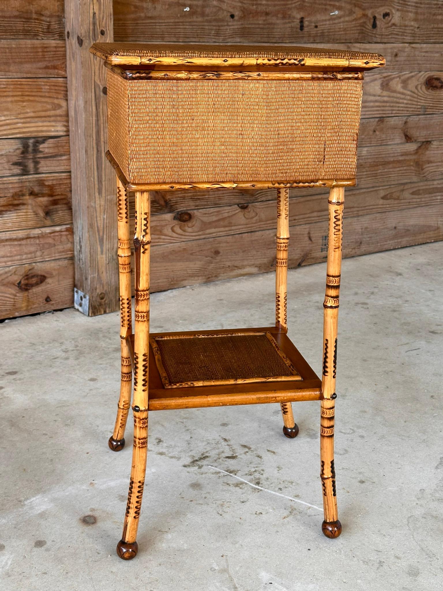 This elegant Late 19th Century English sewing stand is crafted from finely scorched bamboo, Grasscloth with wear and stains, showcasing the intricate artistry and craftsmanship of the era.
Recently refinished to restore its original charm, this