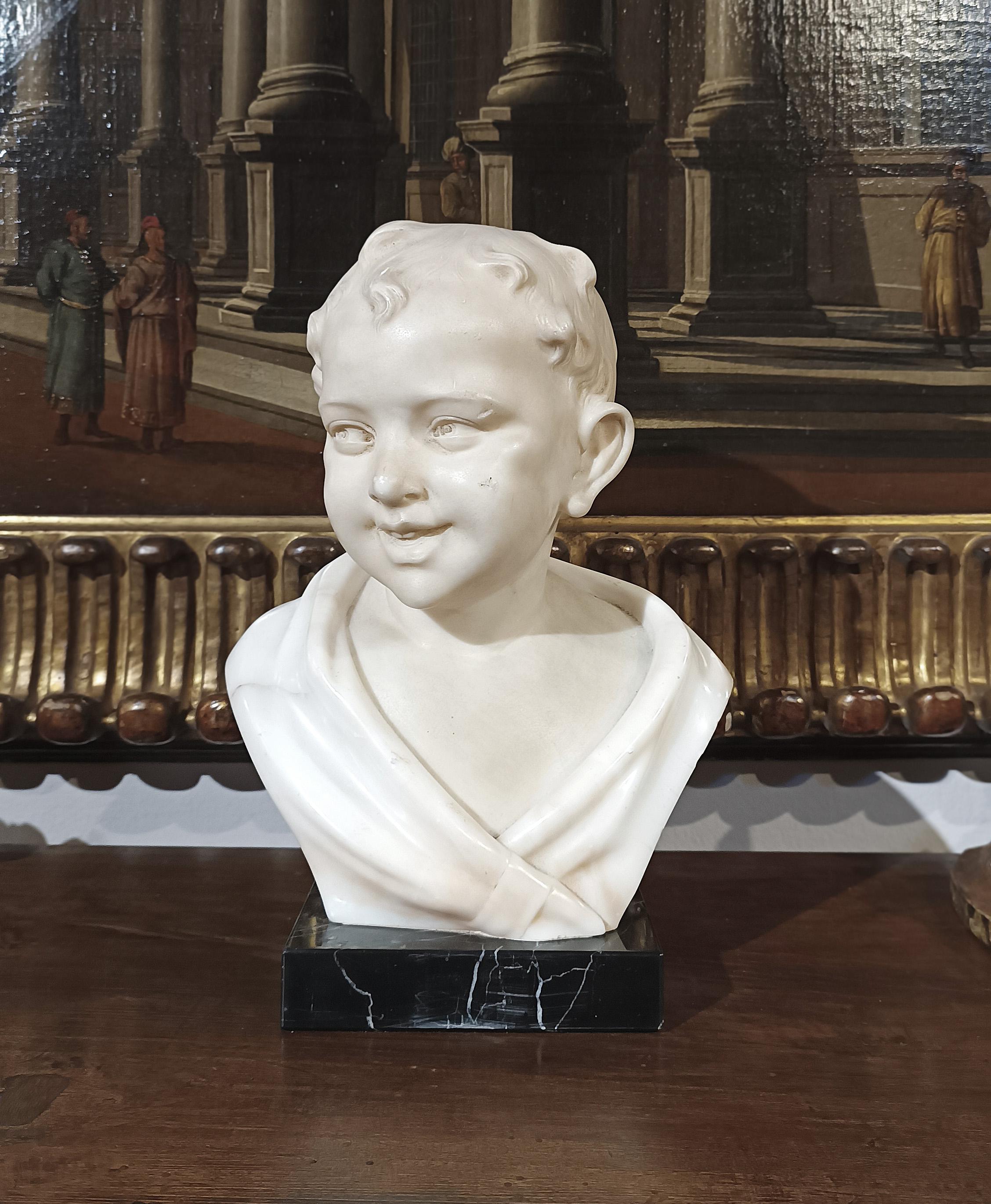 A beautiful white marble sculpture, characterized by a few gray veins, mounted on a black marble base with small white veins. The sculpture depicts a smiling child, his face slightly turned, half-length, dressed in a swaddling robe. The distinctive