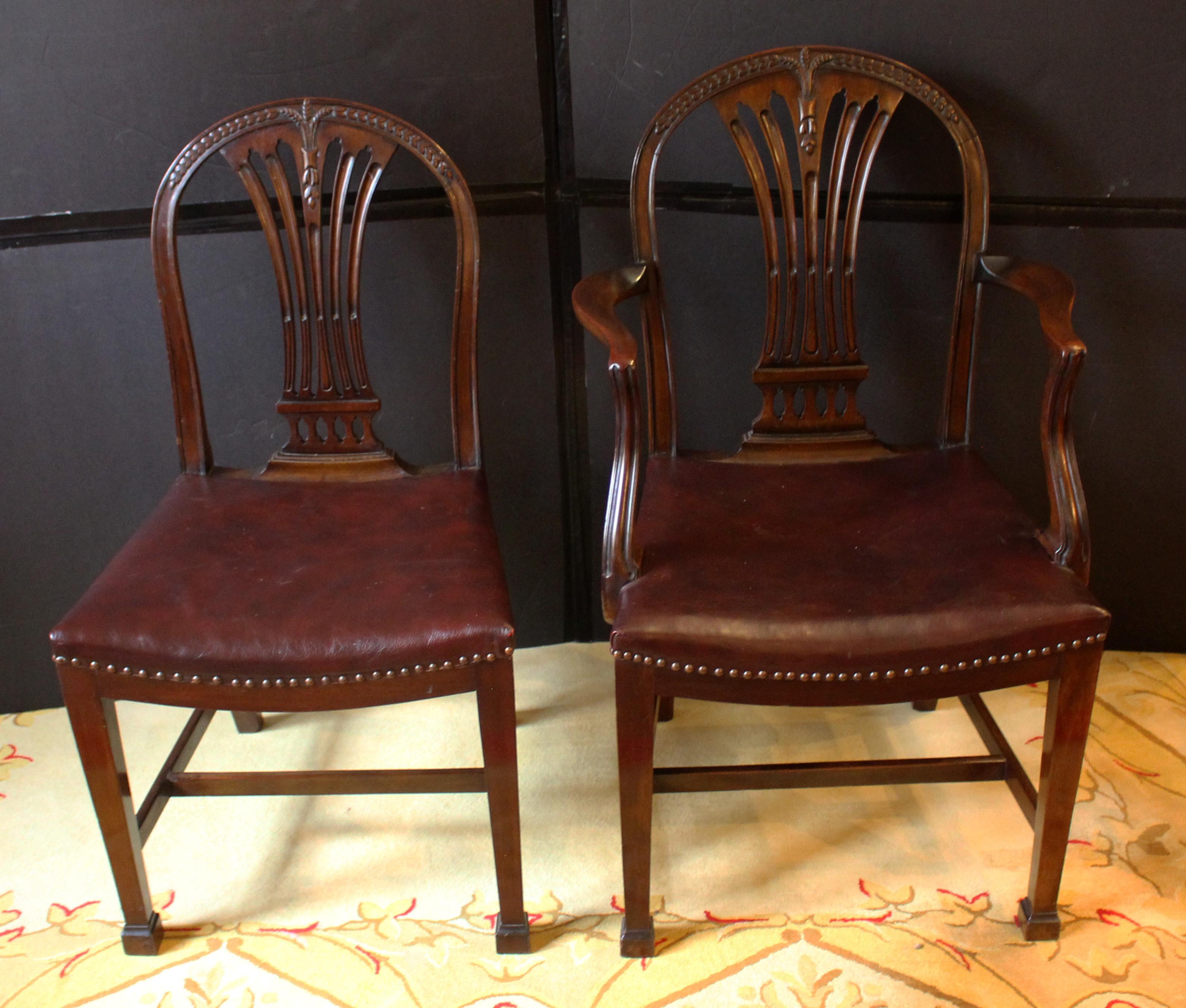 Late 19th century set of 8 dining chairs, English, Hepplewhite style. Mahogany. 2 arms & 6 sides. Leather upholstered saddle seats. Wheat & bellflower carved crests. Cut work backplats with molding & stop fluting over a colonnade. Marlborough front