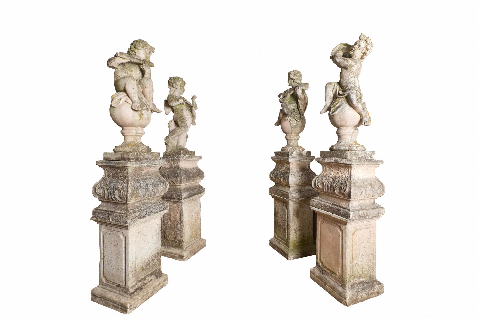 Late 19th century set of four Baroque style cast stone putti, each figure modelled playing a different instrument; flute, lute, and tambourine. One sole Putti represents cupid holding his bow and arrow aloft. The collection of Putti are variously