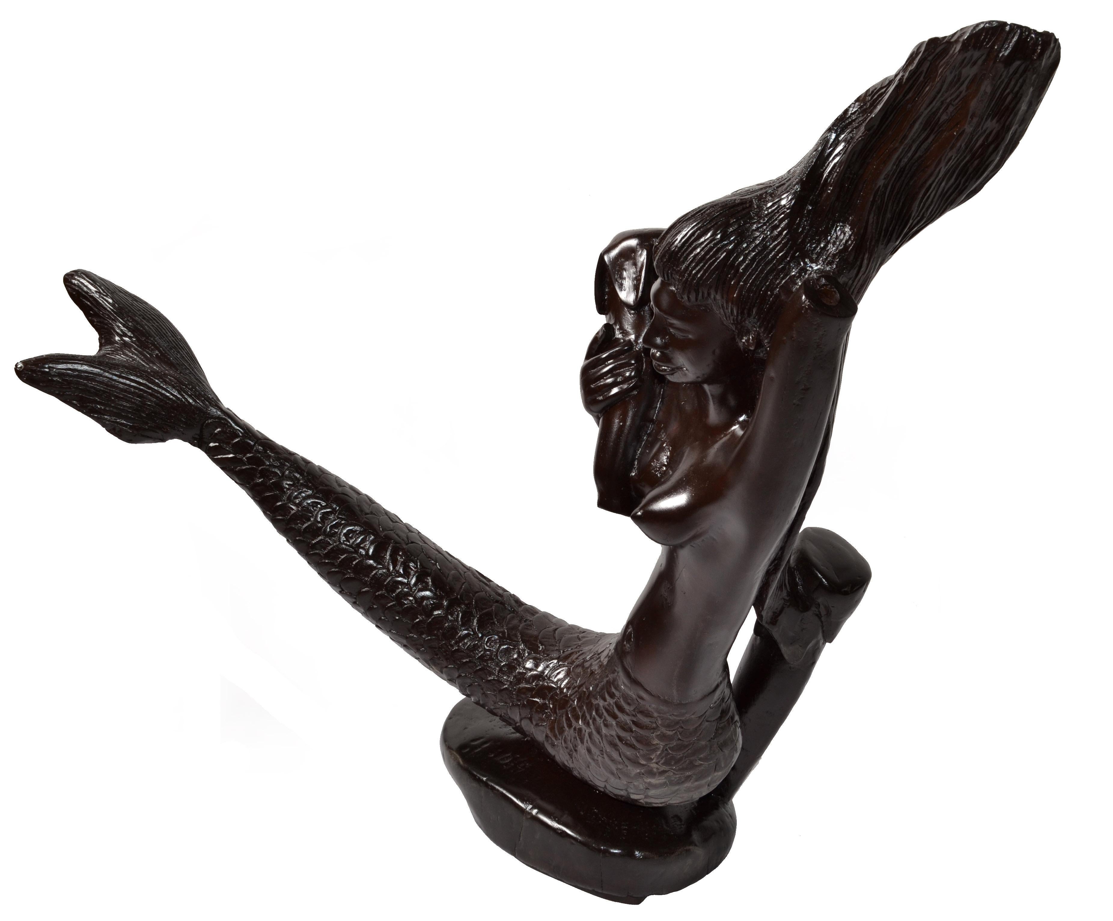 Charmante sculpture de sirène en acajou, unique en son genre, datant de la fin du 19e siècle, sculptée à la main dans une seule pièce de bois massif.
Très détaillées les sculptures texturées des cheveux et de la queue, et la sensibilité du sculpteur