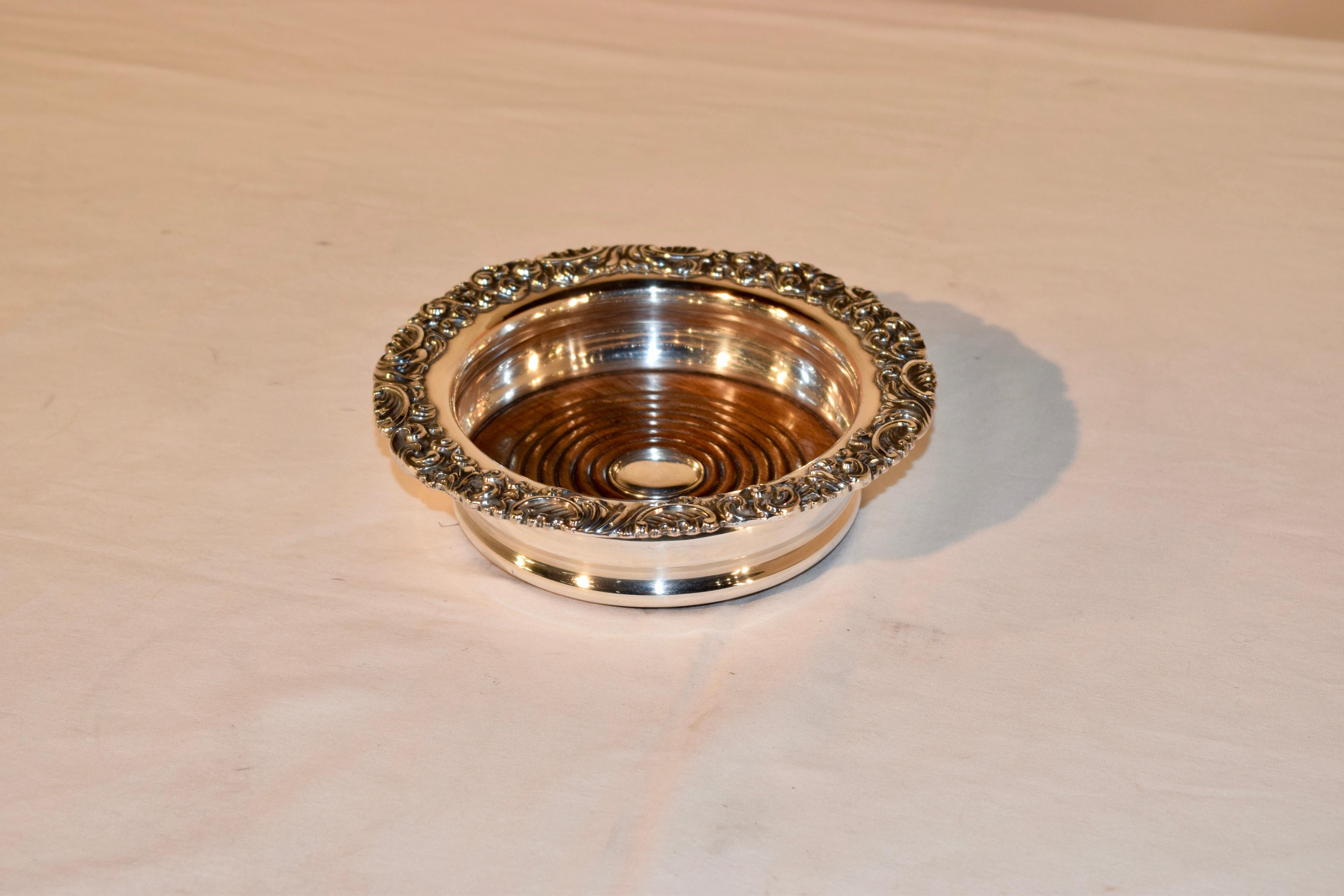 Late 19th century silver plated wine coaster from England with a lovely molded rim and a ridged oak base which has a silver plated medallion in the center.