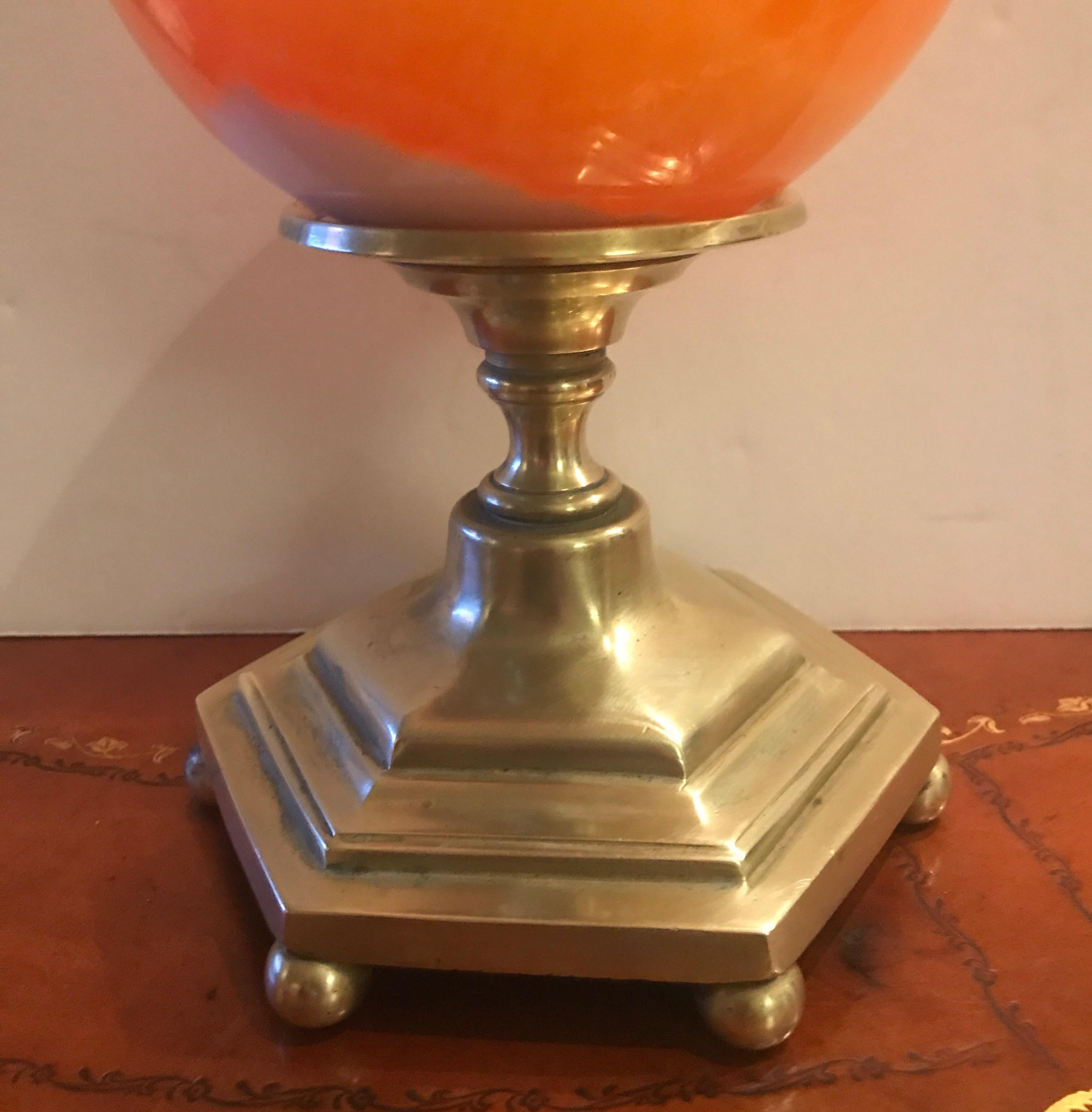 A polished agate sphere with case brass base. The melon colored sphere with white veining resting on a six sided cast brass base. The sphere is 6 inches in diameter and a full 10.5 inches tall on the stand.