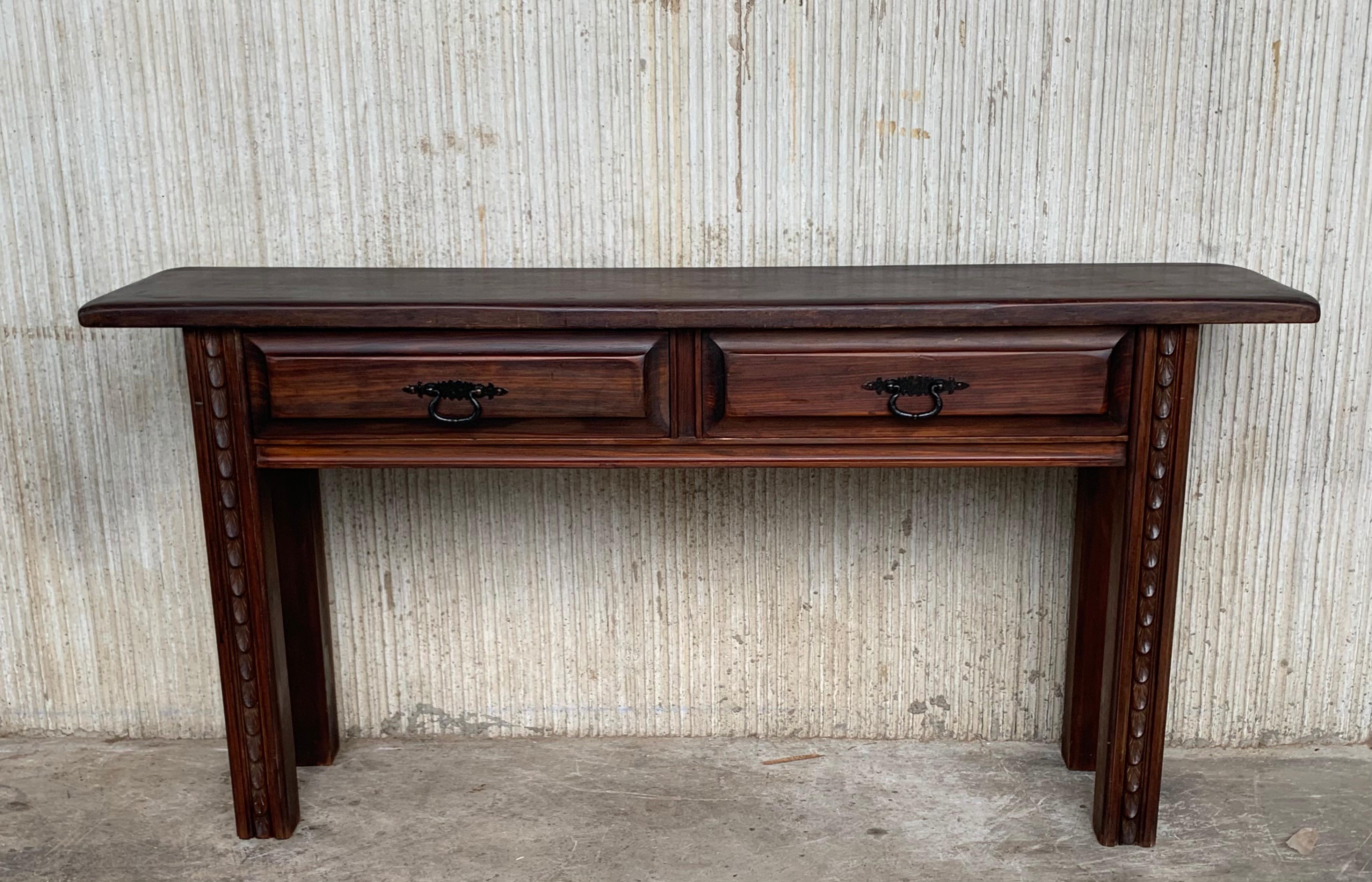 An 19th century Spanish Baroque console, or writing table made of solid walnut with carved shaped legs. Two dovetailed drawers with original iron drawer pulls. The top is made from a single plank of walnut with beautiful grain. Nice character to the