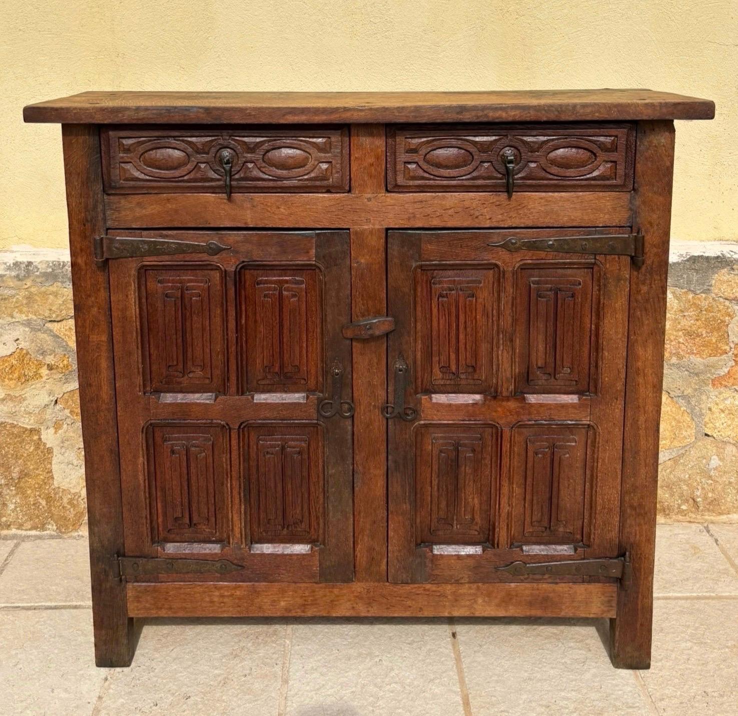 Bellissimo mobile in quercia spagnola della fine del XIX o dell'inizio del XX secolo con ante e cassetti riccamente intagliati a mano. La struttura in rovere massiccio presenta una patina calda e naturalmente invecchiata e una falegnameria