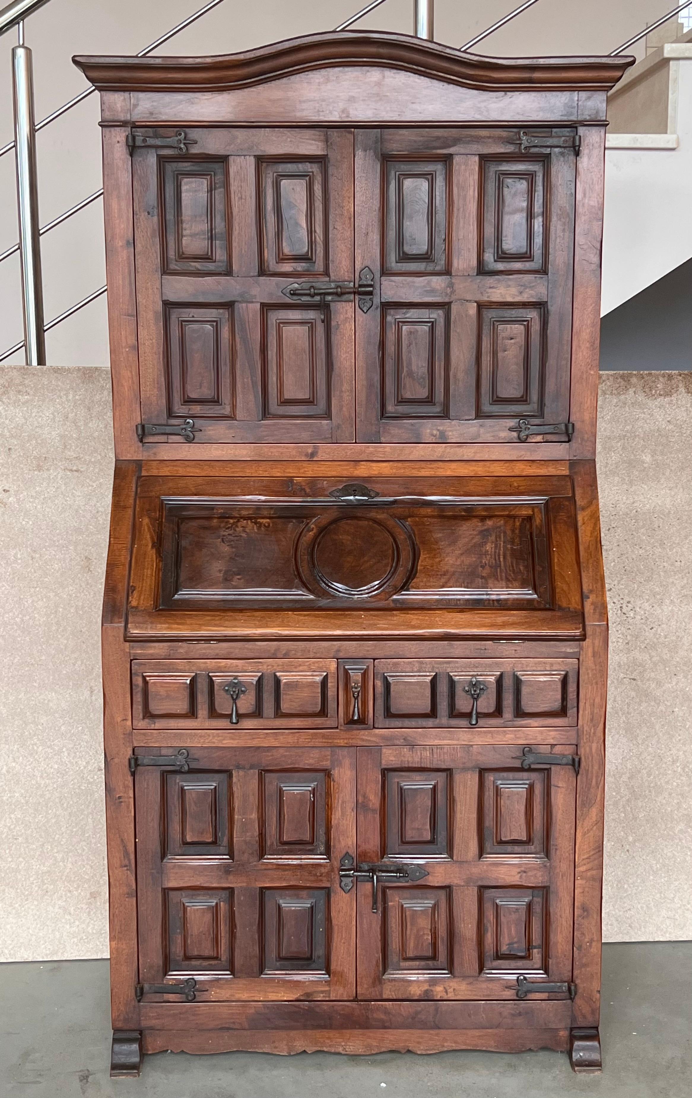 A late 19th century Spanish Walnut Bureau bookcase ‘secretaire’ with fretwork open swan neck pediment, centred by a shaped finial, above a pair of doors, slant front enclosed writing surface, fitted drawers and cubbies and below three graduated wide