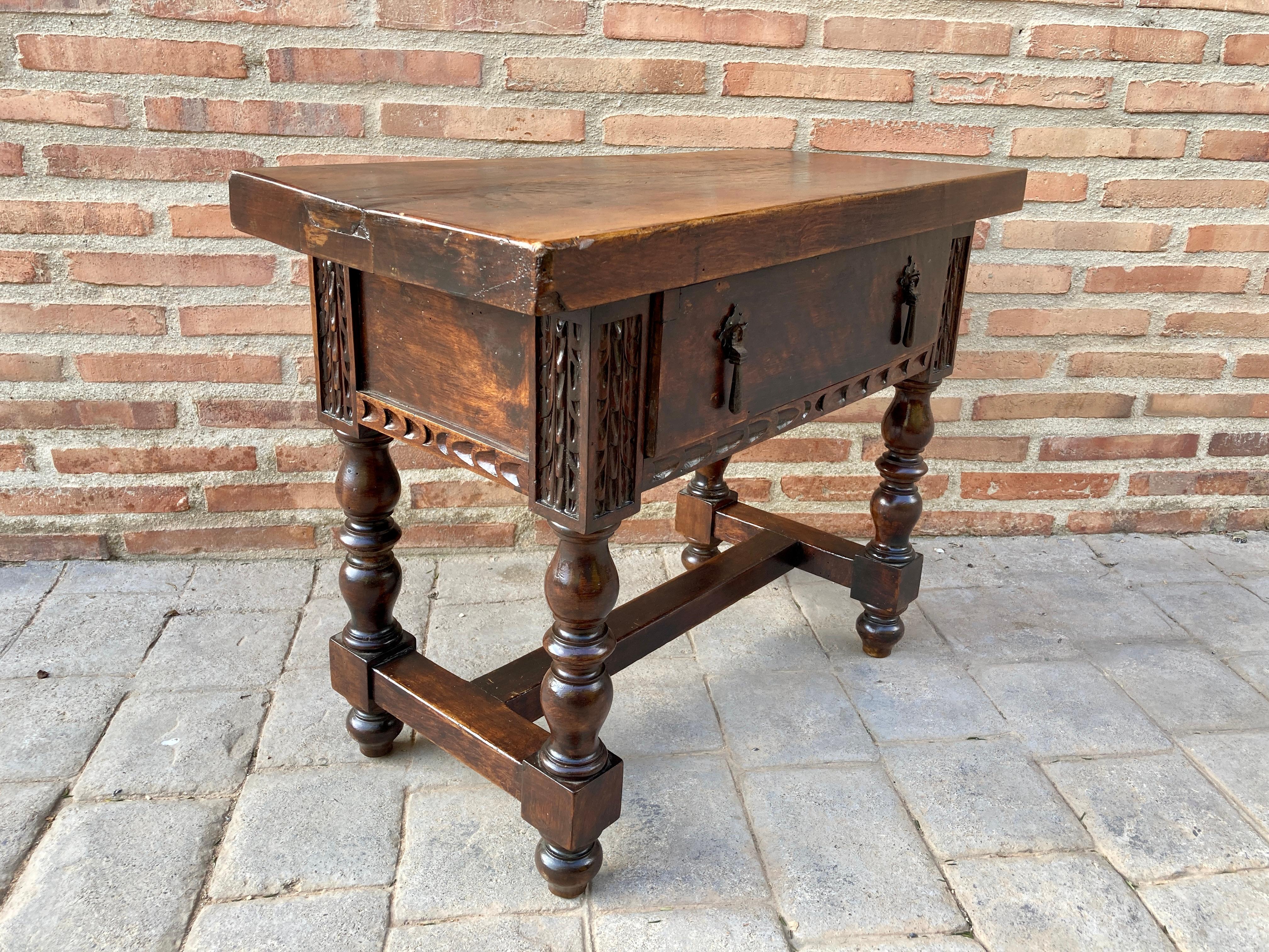 Walnut side table from the 19th century from Spain with a plank top, around the chest of drawers a hand-carved decorated molded edge and a drawer with very old iron handles, on the sides with carved panels and containing a single drawer in The