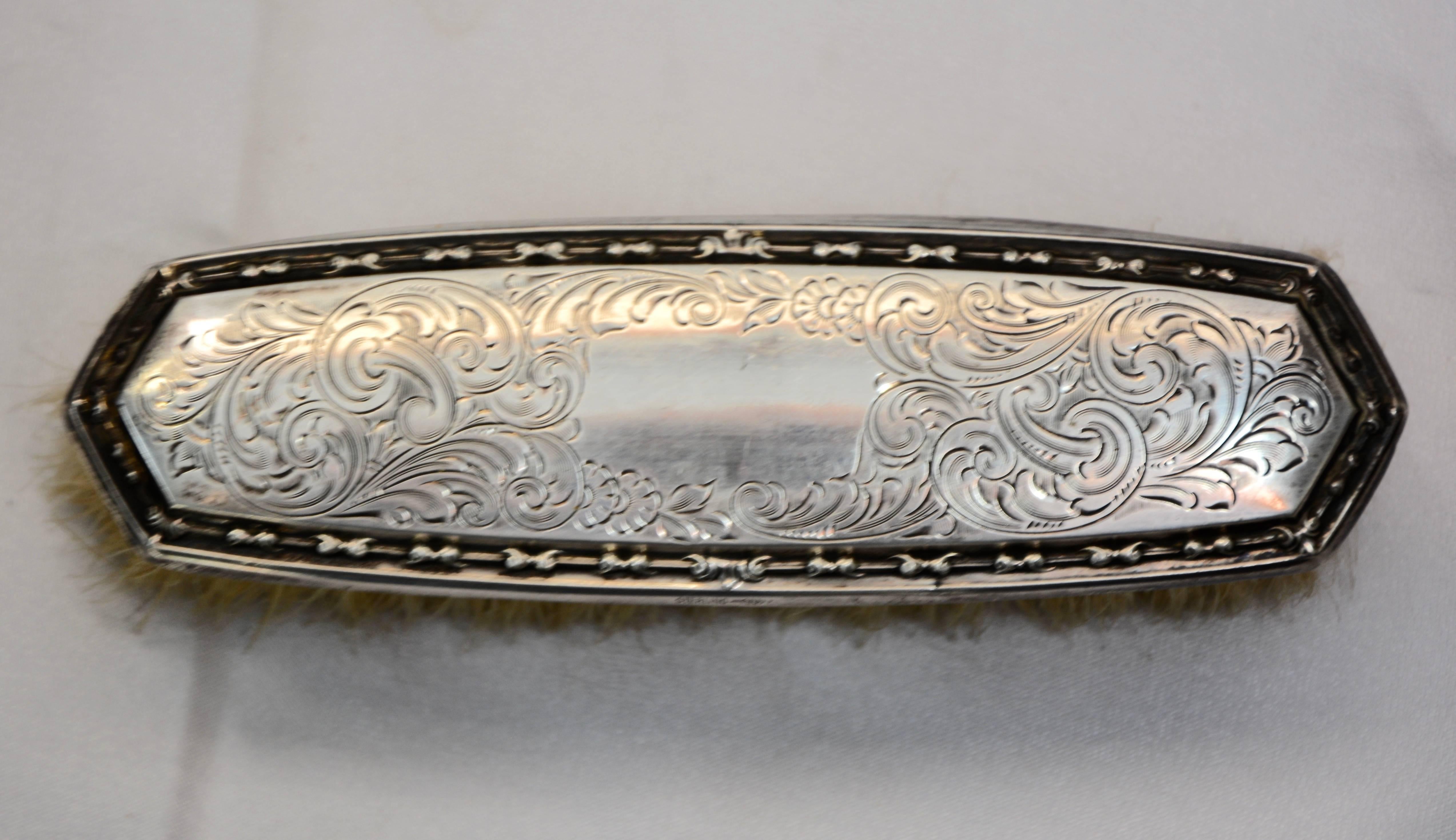 The George K. Webster Company of North Attelboro, Massachusetts, designed this Victorian clothes brush in the late 19th century. The sterling silver is engraved in ornate swirls and the embossed border encircles the design. The piece is marked