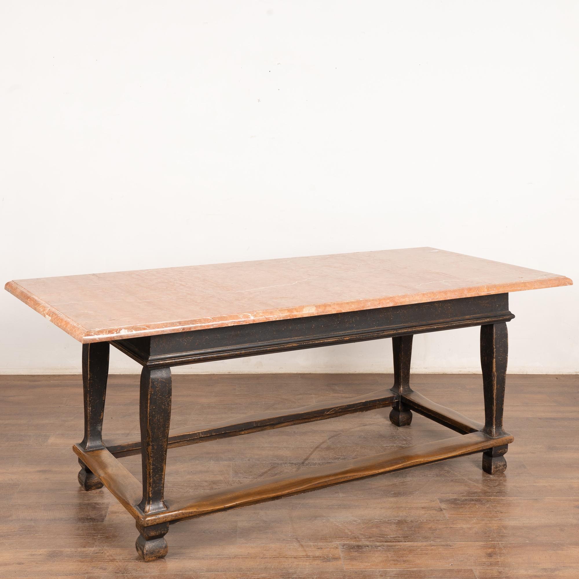 This baroque style library table features a stone top; the base rests on heavy turned legs and trestle. The black painted finish shows distress and reveals the natural wood below.
Please examine photos to appreciate the patina and matrix of the