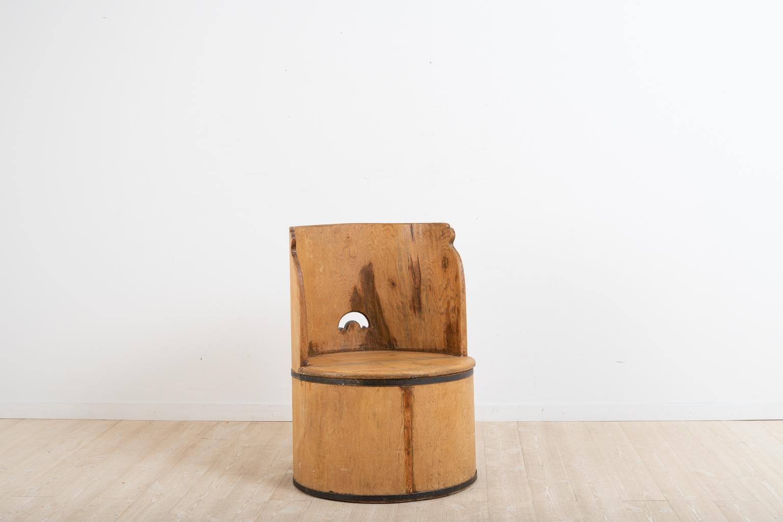 Schwedischer Baumstumpfstuhl, hergestellt aus einem ausgehöhlten Baumstamm. Der Stuhl ist primitiv und wurde nie gestrichen. Die beiden Bänder, die den Sitz umgeben, sind handgeschmiedet und dienen der Verstärkung der Konstruktion sowie als
