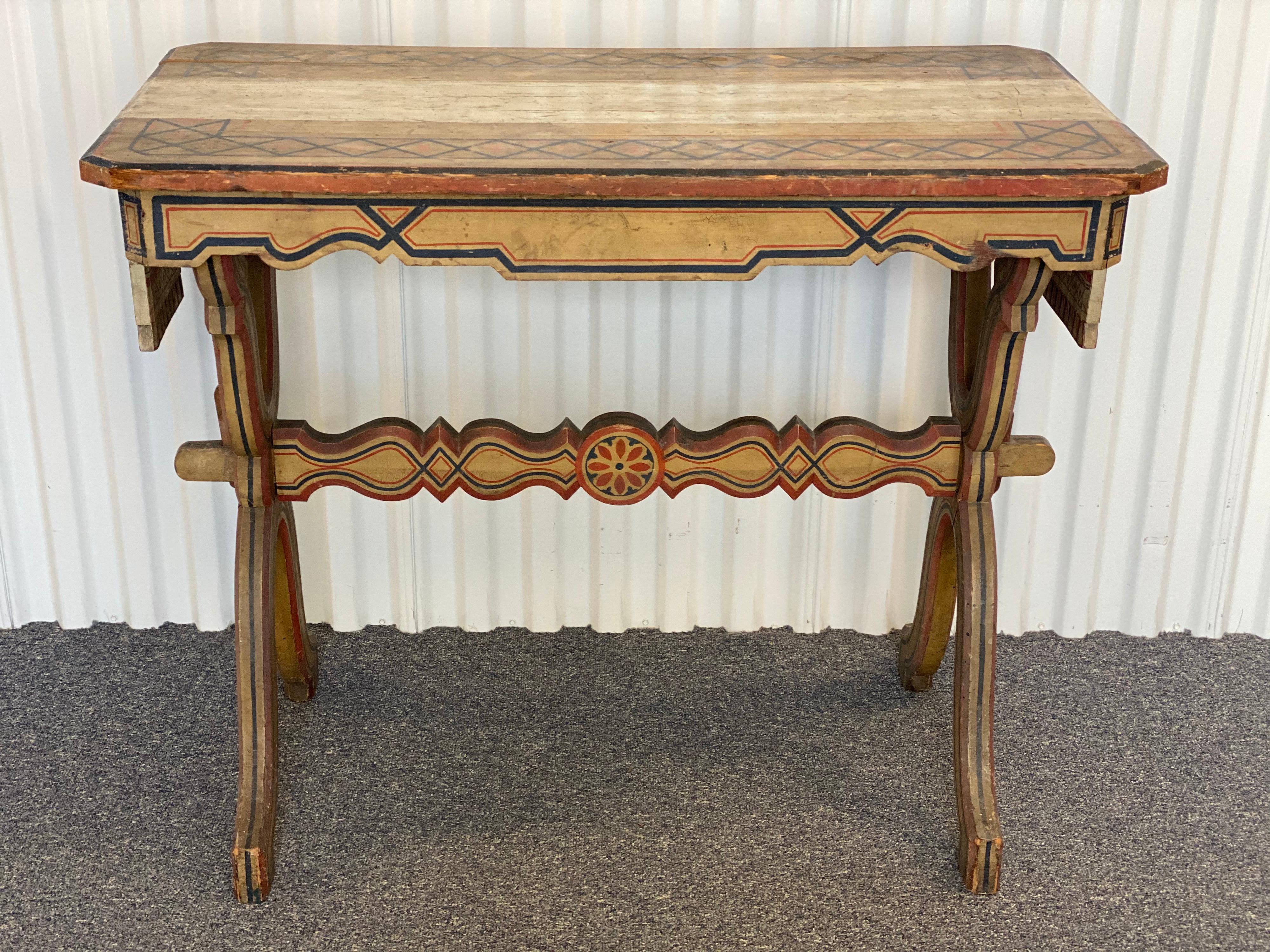 Late 19th century Swedish painted console table.
Elaborately hand painted console in navy, vermillion, and a faded yellow-cream palette. This unique piece has a runner that has been hand carved into the table itself and cascades beautifully off the