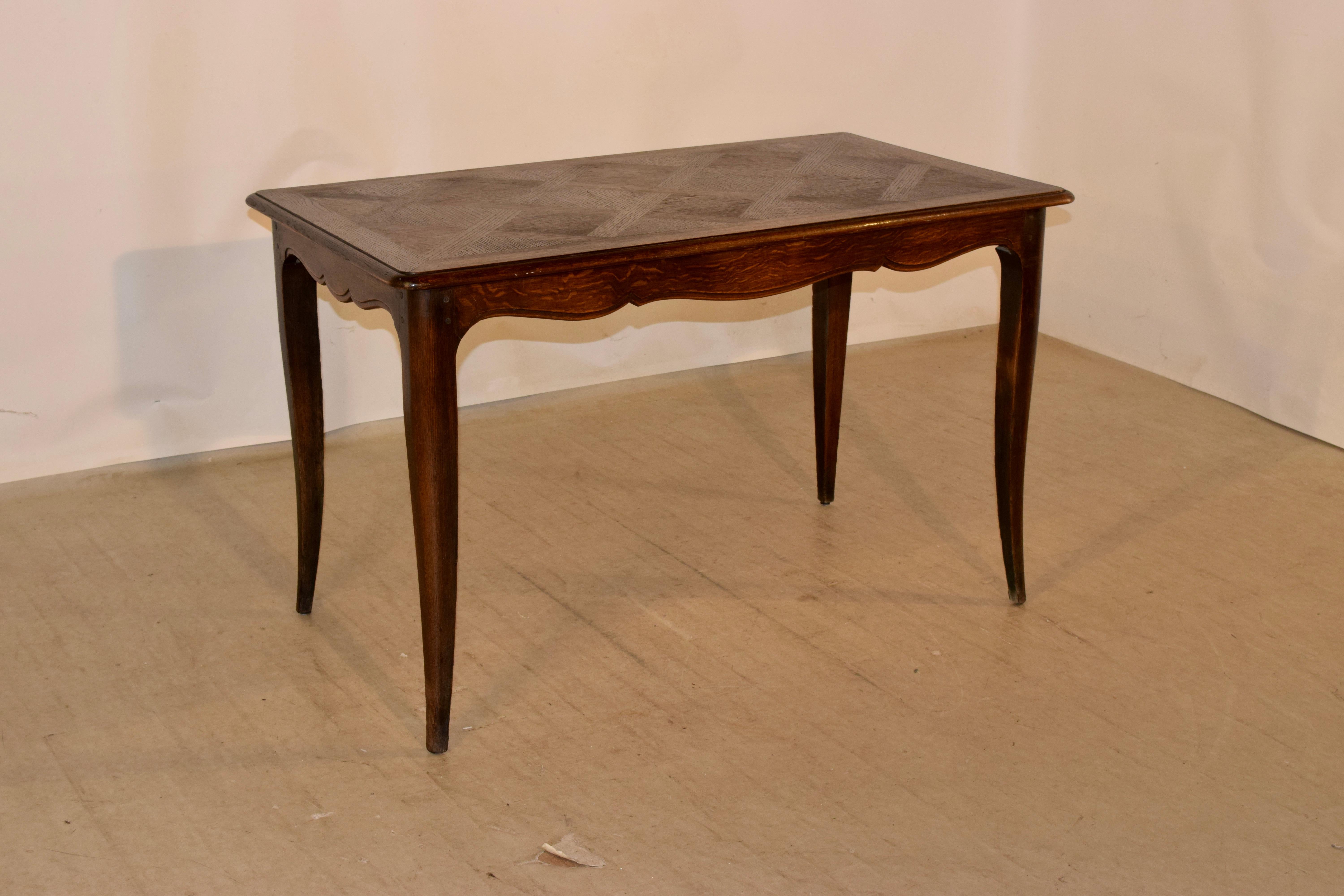 Tisch aus dem späten 19. Jahrhundert mit einer schönen gebänderten und abgeschrägten Kante, die eine zentrale Parkettplatte umgibt. Die Schürze ist gezackt und hat eine abgeschrägte Kante. Der Tisch steht auf gespreizten Cabriole-Beinen. Die Schürze