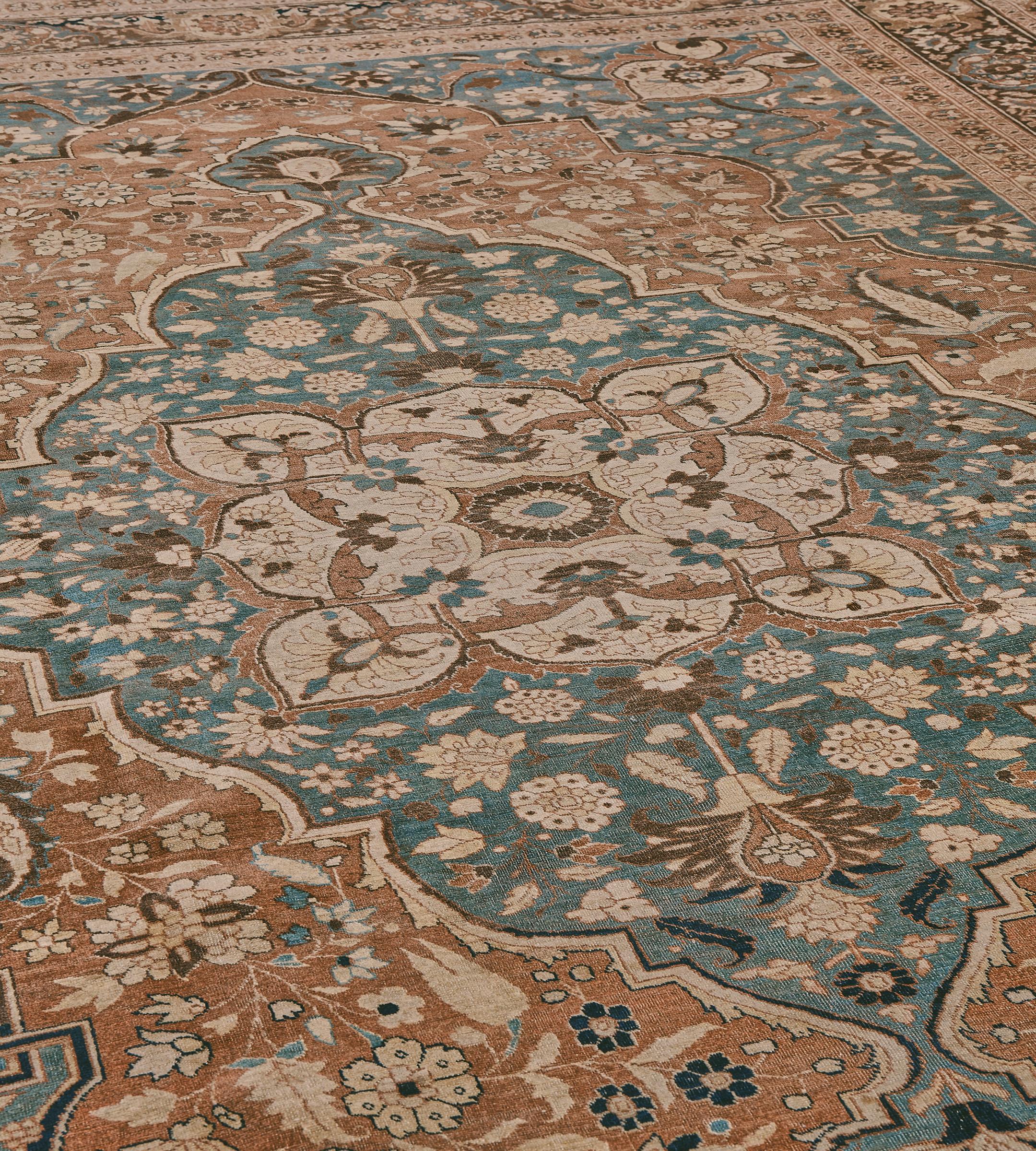 Esta alfombra tradicional persa de Tabriz, tejida a mano, tiene un campo de óxido envejecido contrapuesto por serpenteantes aerosoles florales, que encierra un medallón imperial azul medio de motivo similar que irradia desde un ornamentado foco de