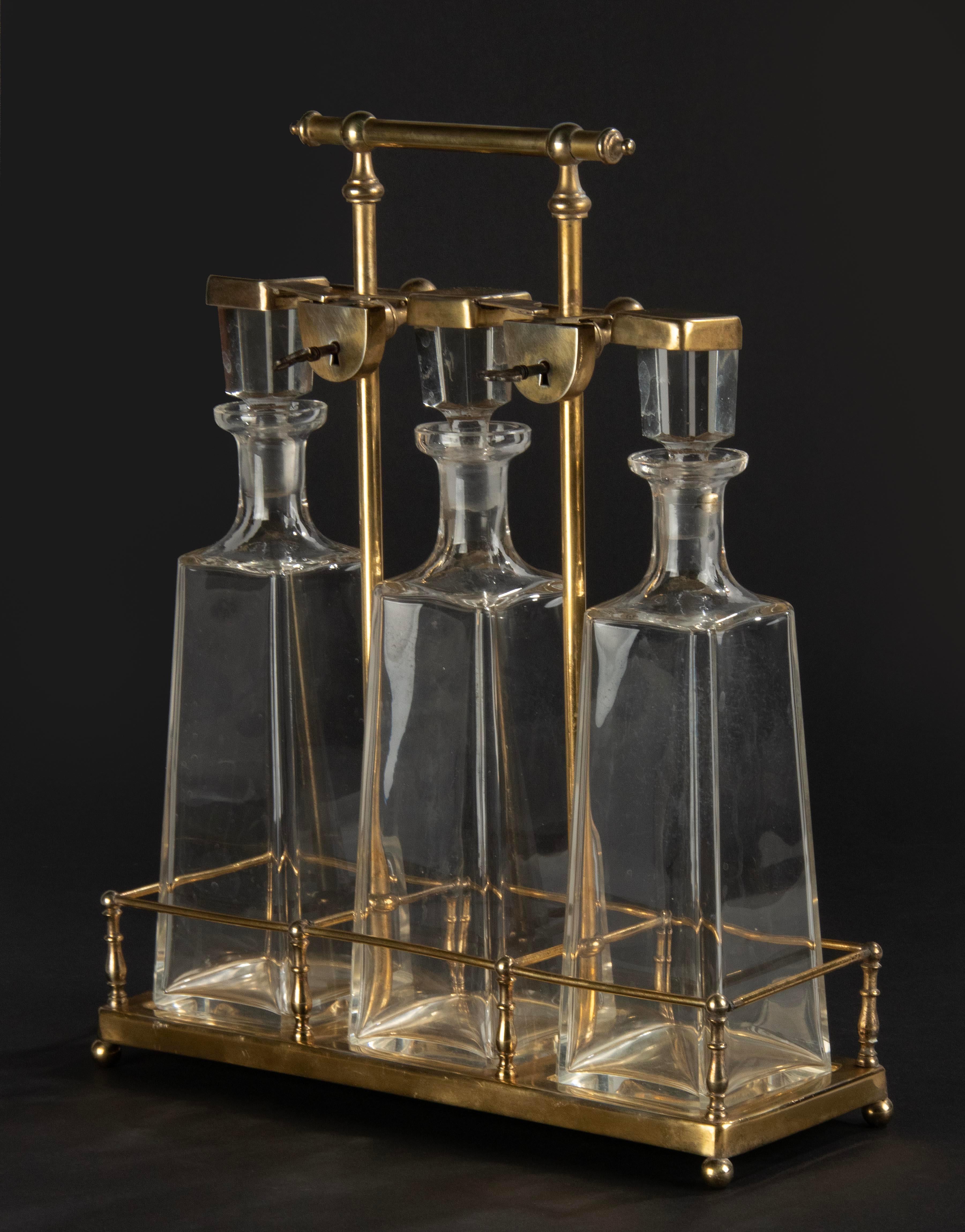An antique brass colored tantalus rack with three large crystal decanters. The decanters and stoppers are original and antique. The tantalus can be closed with working locks. Made in France around 1880-1890.

Dimension tantalus: 38 (h) x 33 x 12