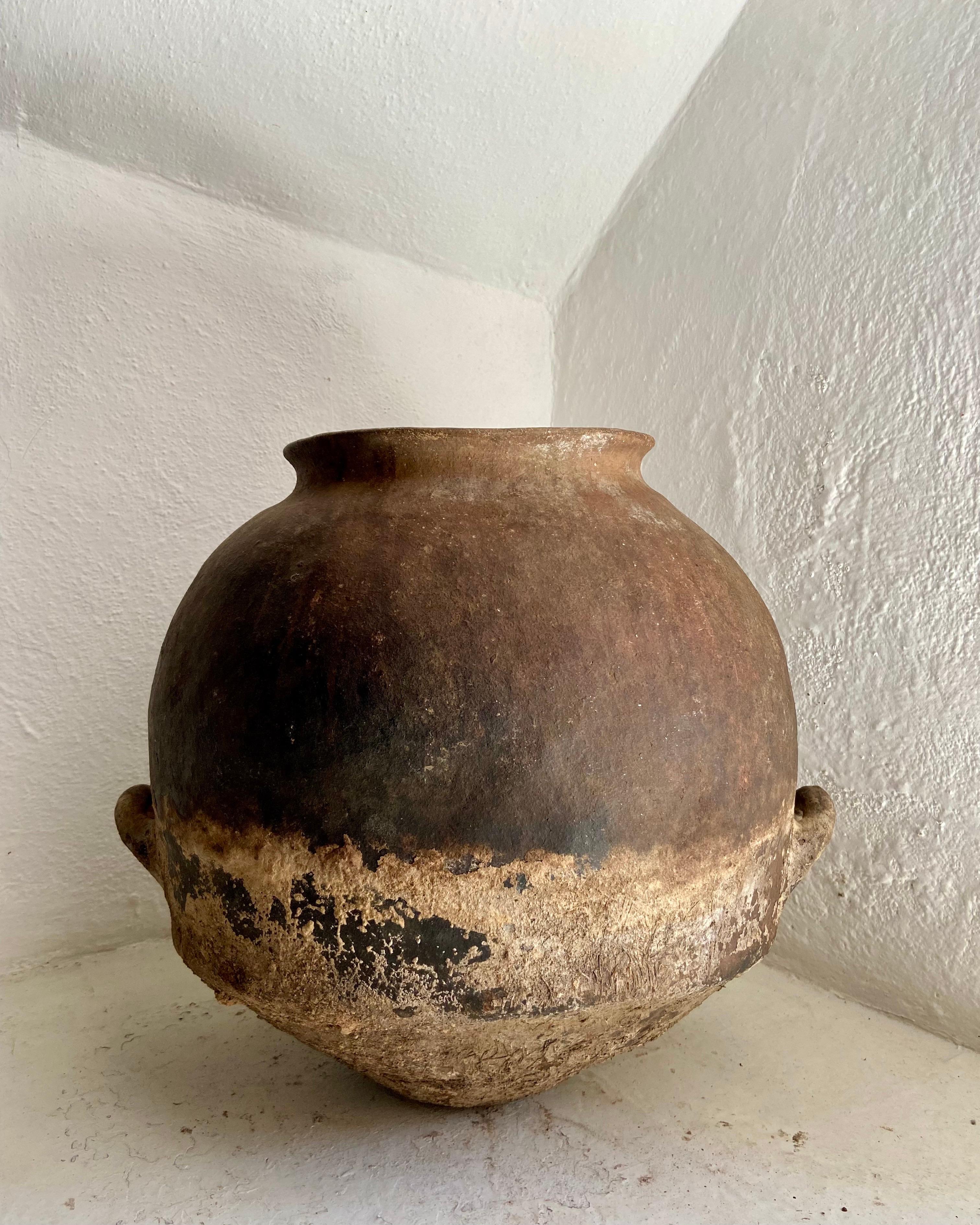 Late 19th century terracotta water jar from Northern Puebla, bordering with Veracruz, Mexico. Wide format pot with intact handles. Th pot has deep brown colors and is heavily weathered.