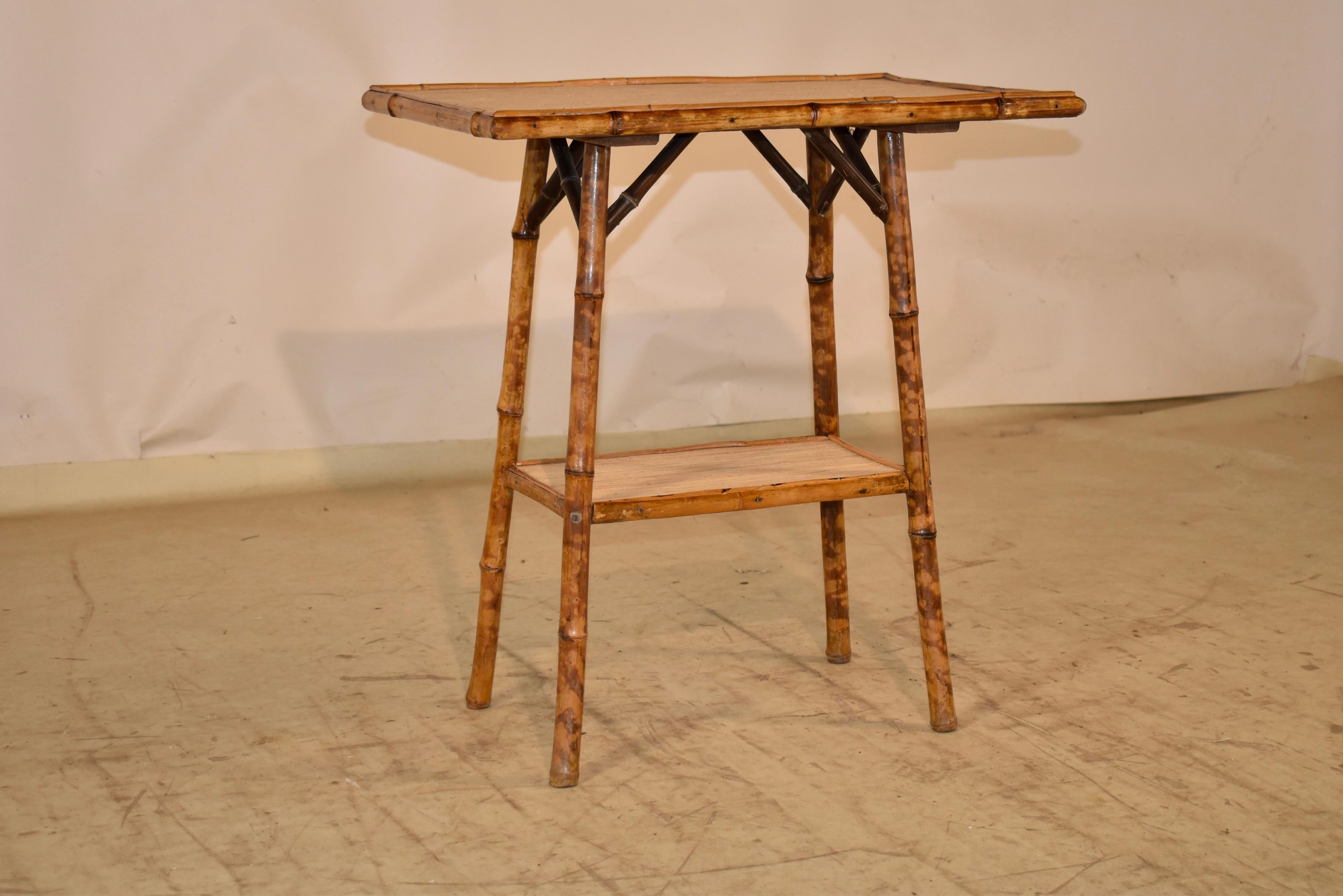 Mesa auxiliar de bambú tortuga de finales del siglo XIX, procedente de Francia.  La parte superior tiene molduras de bambú y se apoya en patas separadas, unidas por un estante inferior, que también tiene bordes moldeados de bambú.  
