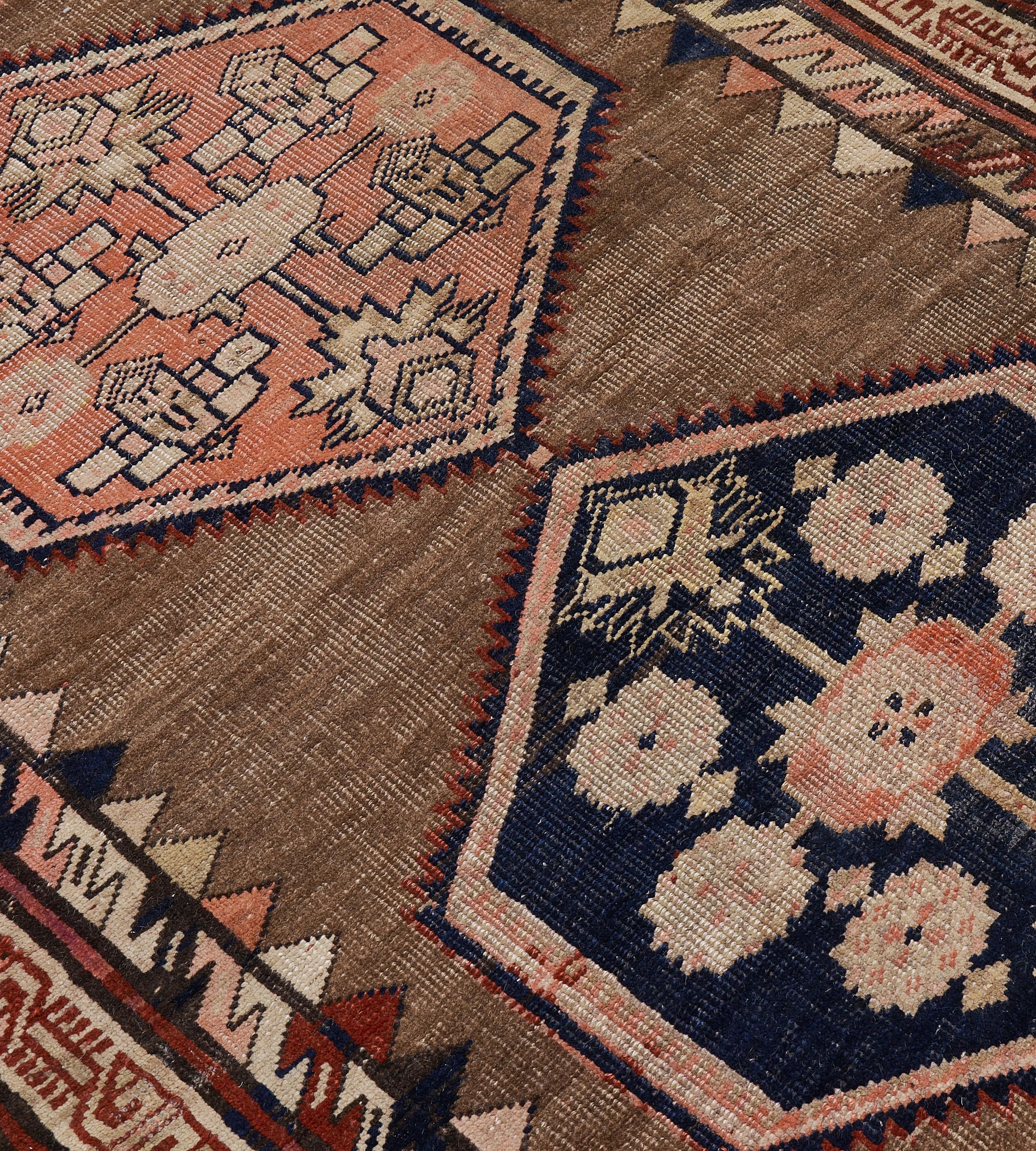 This traditional hand-woven Persian Bidjar rug has a shaded camel brown field with central column of alternating onyx and coral serrated lozenges enclosing radiating floral motif, in double tonal red-brown geometric borders.