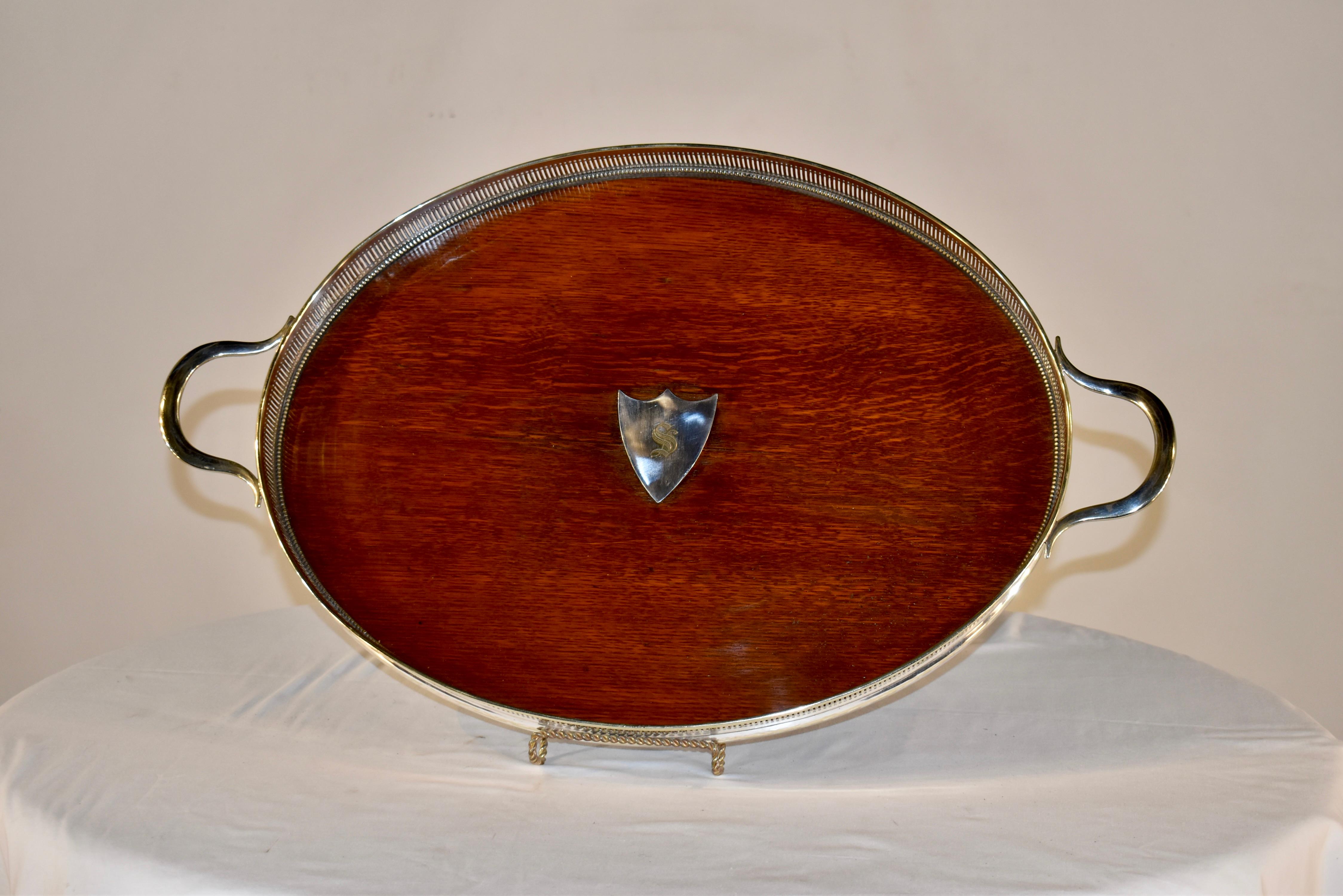 Late 19th century oak gallery tray from England. The gallery is prominent and is silver plated, along with the central shield, which is engraved with a letter S. The feet are silver plated as well. This is a wonderful and very large serving tray,