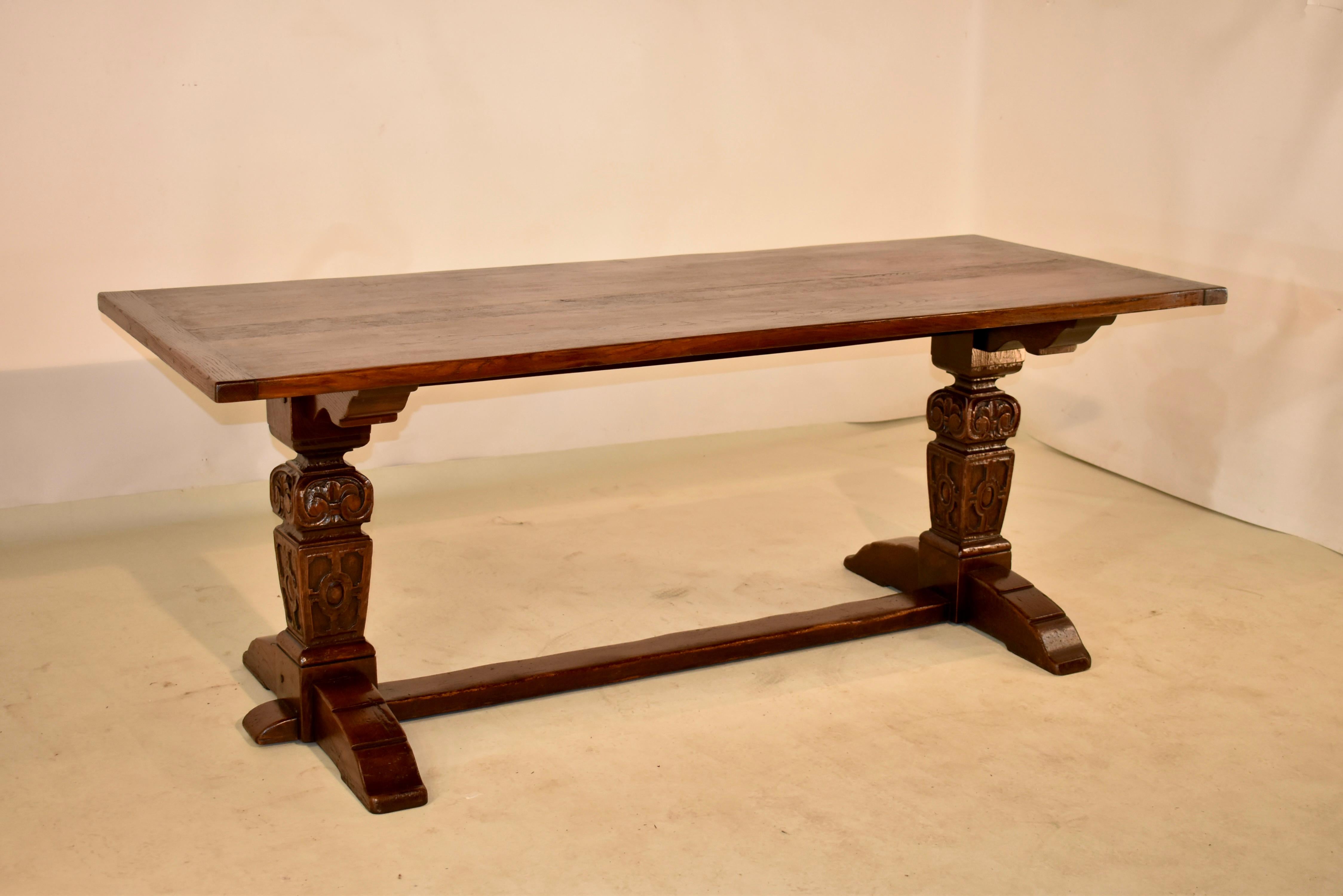 Late 19th century oak trestle table from England. The top is wonderfully grained and has a rich color. This sits atop a trestle base. The legs are hand-turned square and carved decorated and are supported upon a trestle base with a cross stretcher.