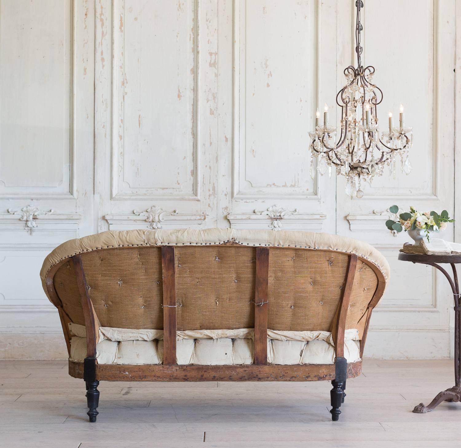 Incredible tufted antique loveseat in original muslin with black legs. The firm cushions provide a balanced and comfortable seating option while the piece itself lends a topic of conversation for a library or small nook.