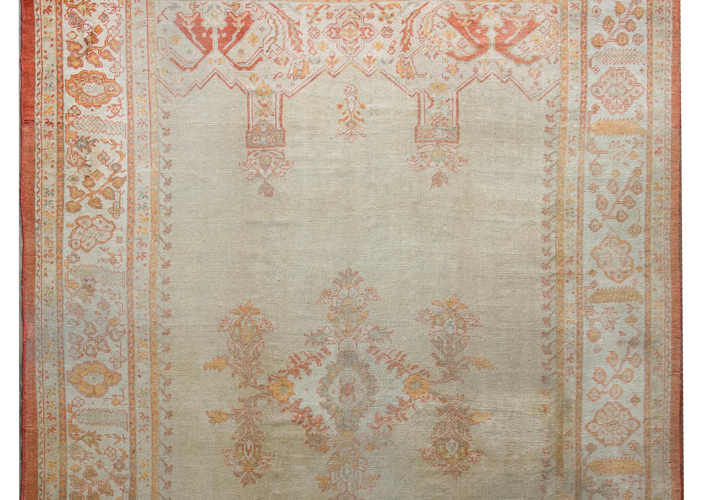 An exceptional and striking late 19th century Turkish Oushak rug with a quiet pattern with a simple floral medallion living amidst a solid cream colored field, and surrounded by an wonderfully wide border containing multiple floral and scrolling