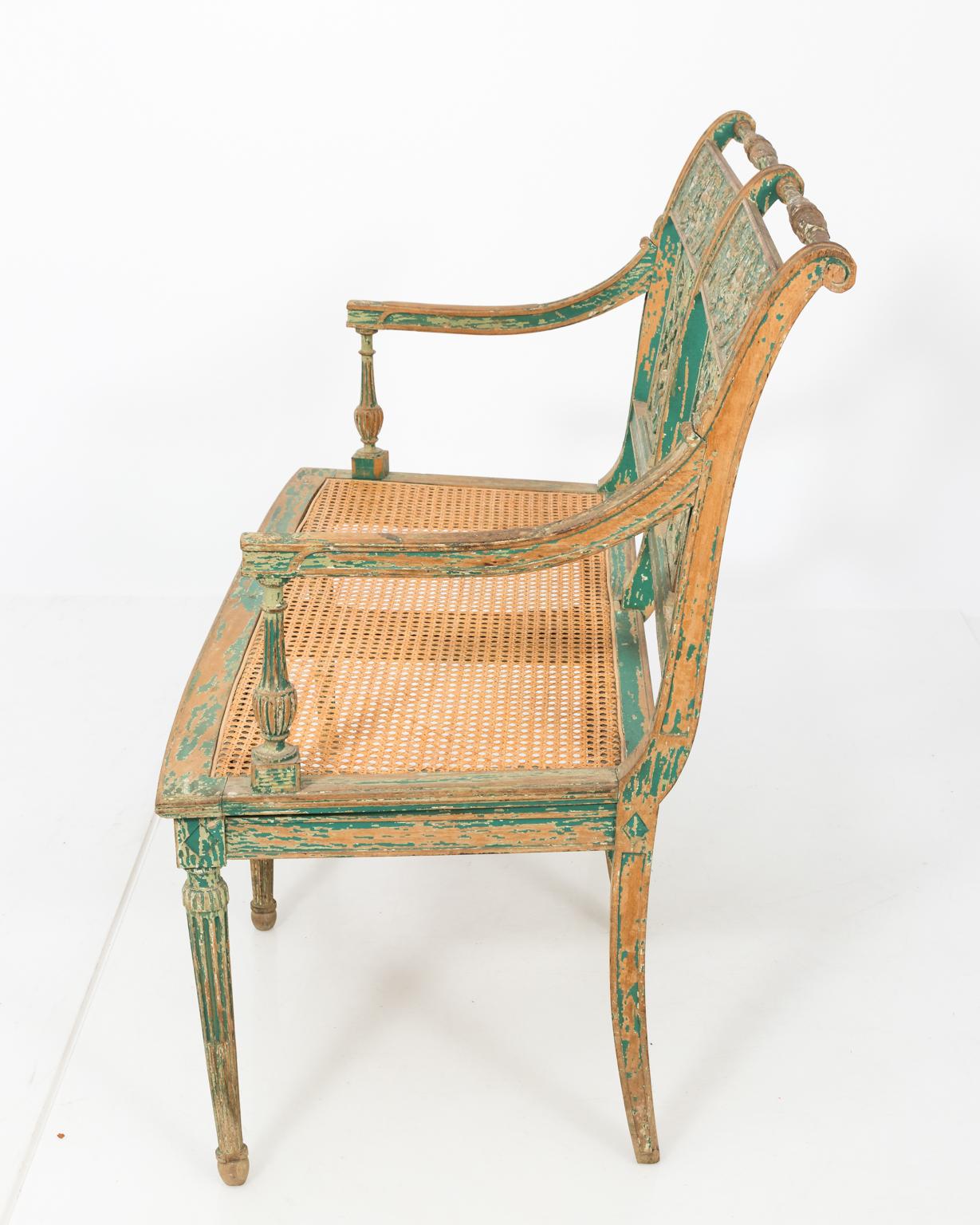 Late 19th century two-seated French painted bench with medallion back splat, caned seating with six legged base.