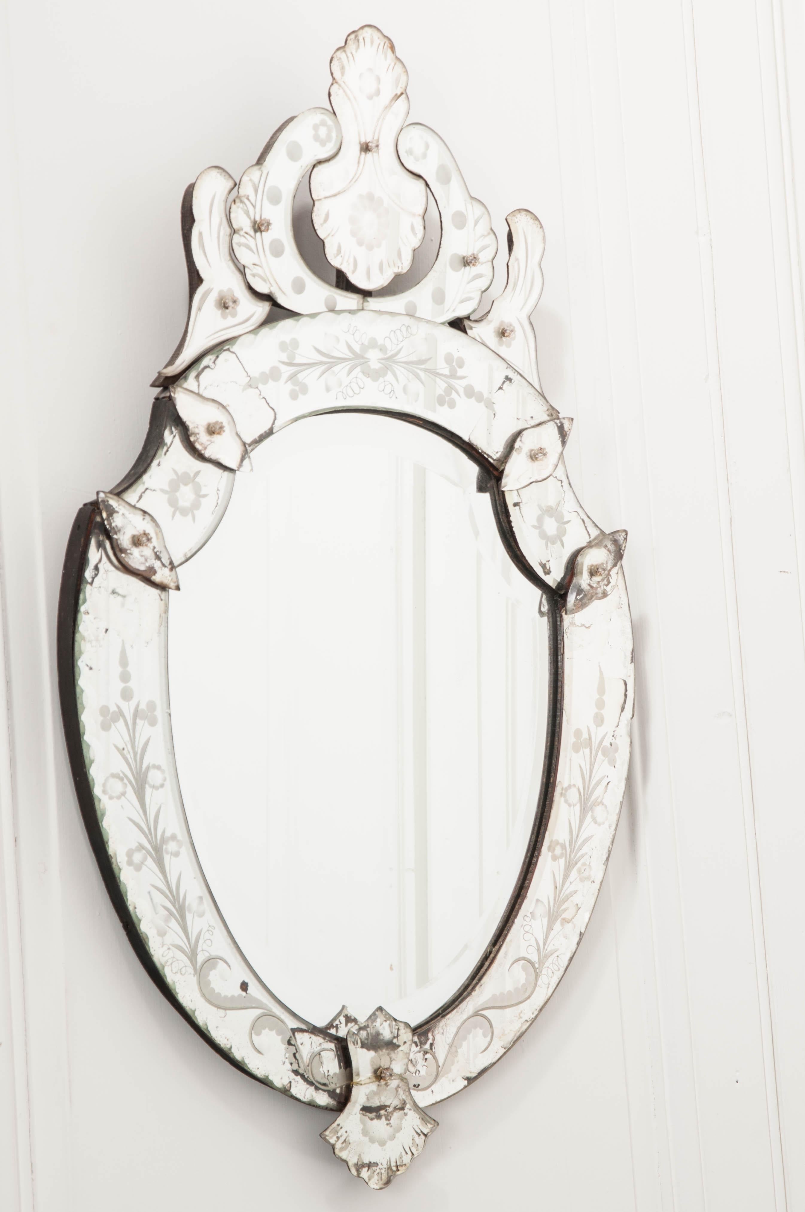 A stunning Venetian wall mirror, with wonderful shield form, from 1880s Italy. The antique uses beautifully shaped mirror pieces, held together with fasteners that are capped in crystal. Every aspect of the mirror is reflective and brilliant. All