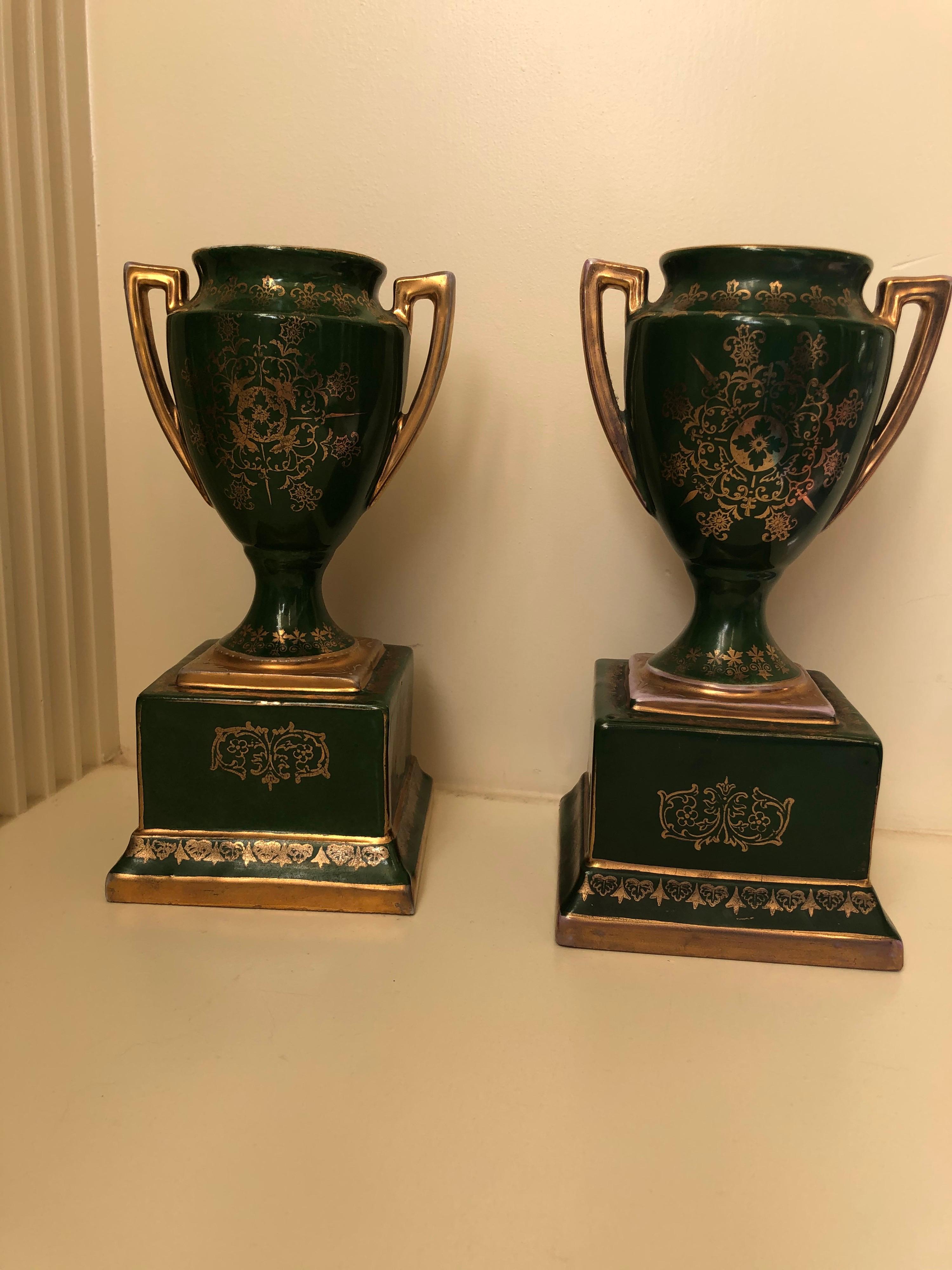 Beautifully decorated green urns from the late 19th century. Nicely decorated with cherubs in flight. Urns are seated on square base and are decorated on all sides.