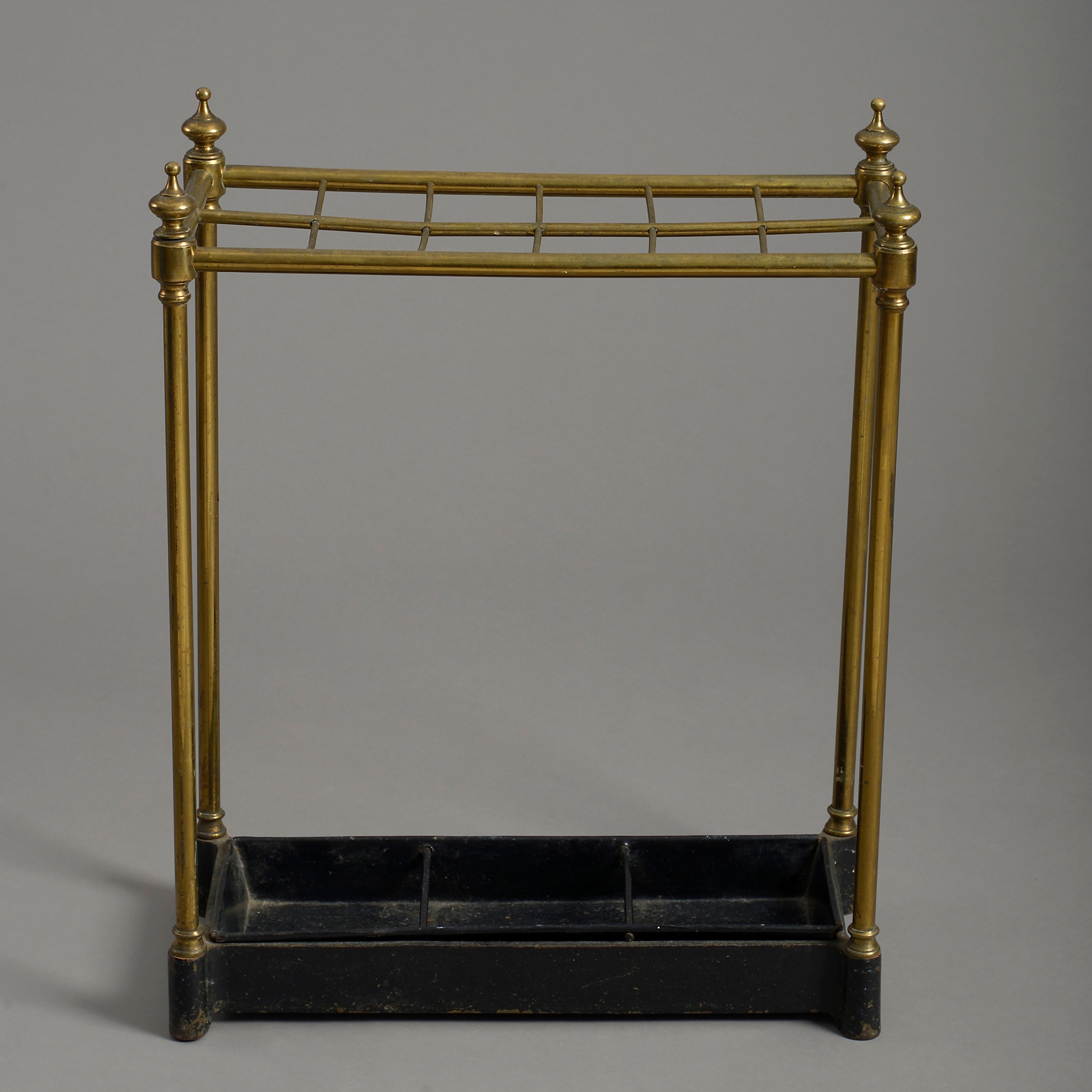 A late 19th century Victorian period stick and umbrella stand, the rectangular brass frame with turned finials, twelve divisions, all set upon a cast iron base with the original tin drip pan.