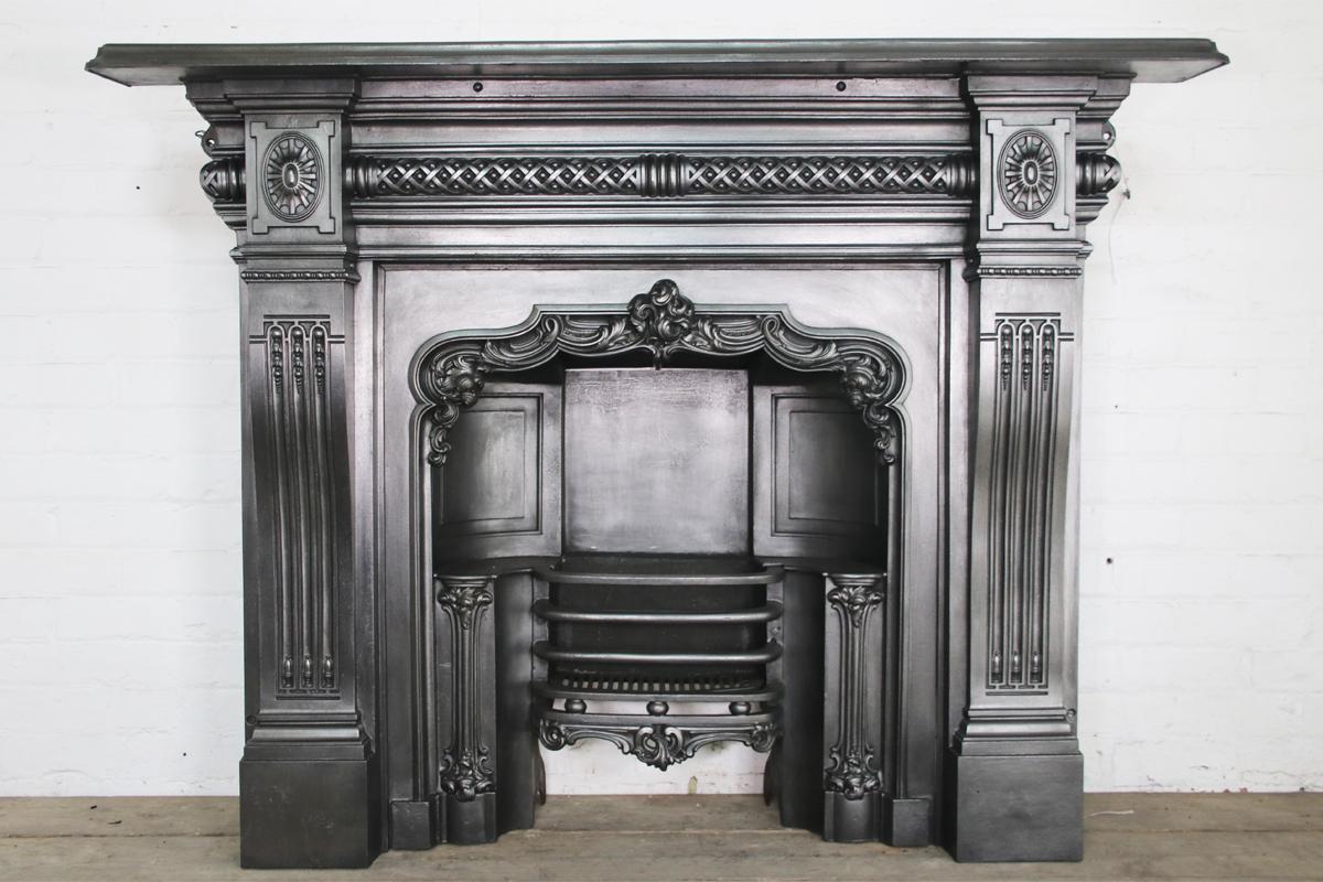 Decorative late 19th century Victorian cast iron fireplace surround with cabriole legs decorated with flutes and bell flowers. The frieze is decorated with deeply cast lattice work flanked by square capitals adorned with paterea. Dated