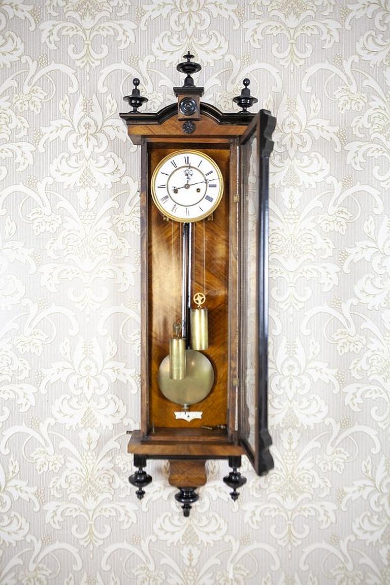 Late-19th Century Wall Clock with Brass Elements in Walnut Case

We present you this wall clock from the late 19th century in a glazed walnut case.
The clock face is porcelain, whereas both the pendulum and weights are made of brass. The clock