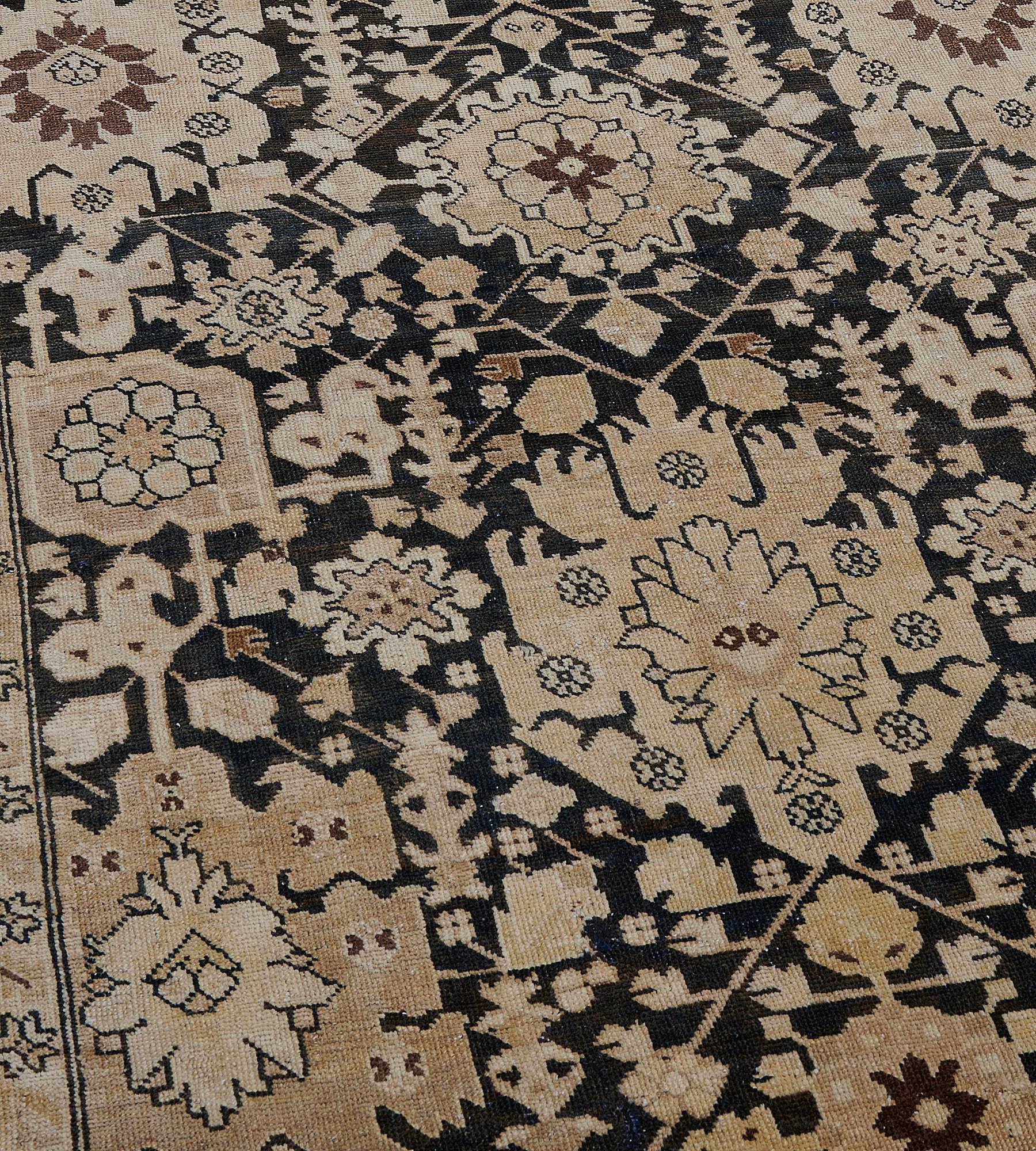 This antique Karabagh rug has a charcoal-brown field with a buff-brown and sandy-brown central column of bold angular palmettes linked by angular floral vine and flanked by similar columns of buff-brown palmettes, in a narrow sandy-yellow border of