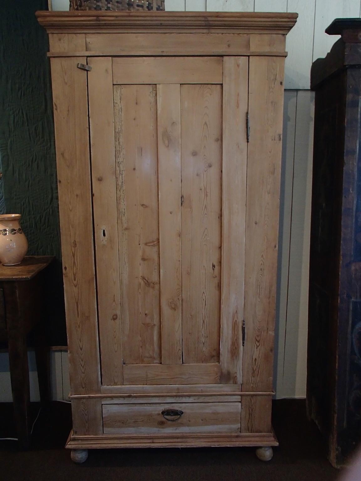Late 19th century yellow pine armoire with single door, lower drawer, resting on bun feet.