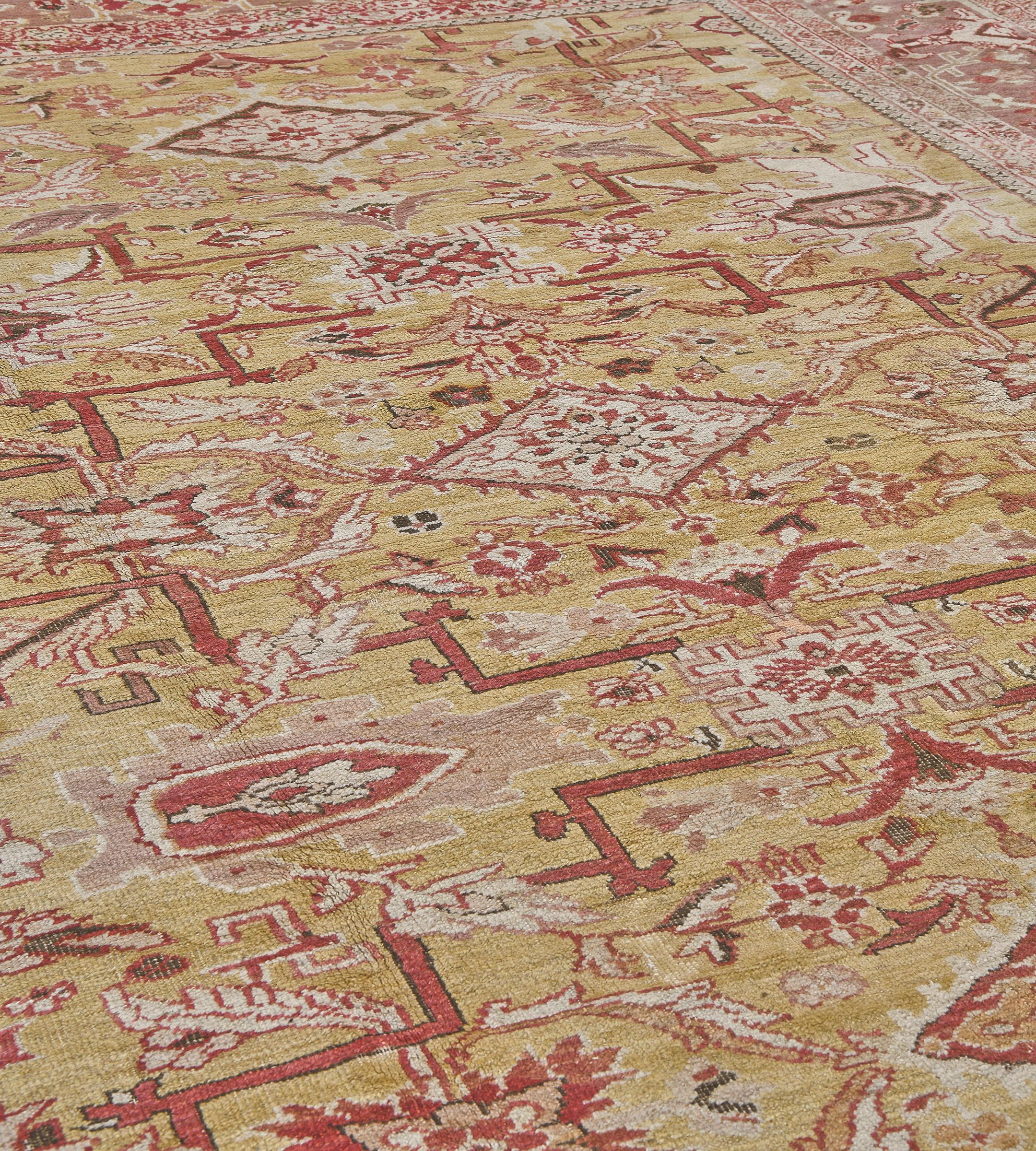 This traditional hand-woven Persian Ziegler Sultanabad rug has an attractive golden saffron field of sparse meandering floral motif, enclosing three floral lozenge medallions, each flanked by stylized geometric trellises, in a shaded flesh colored