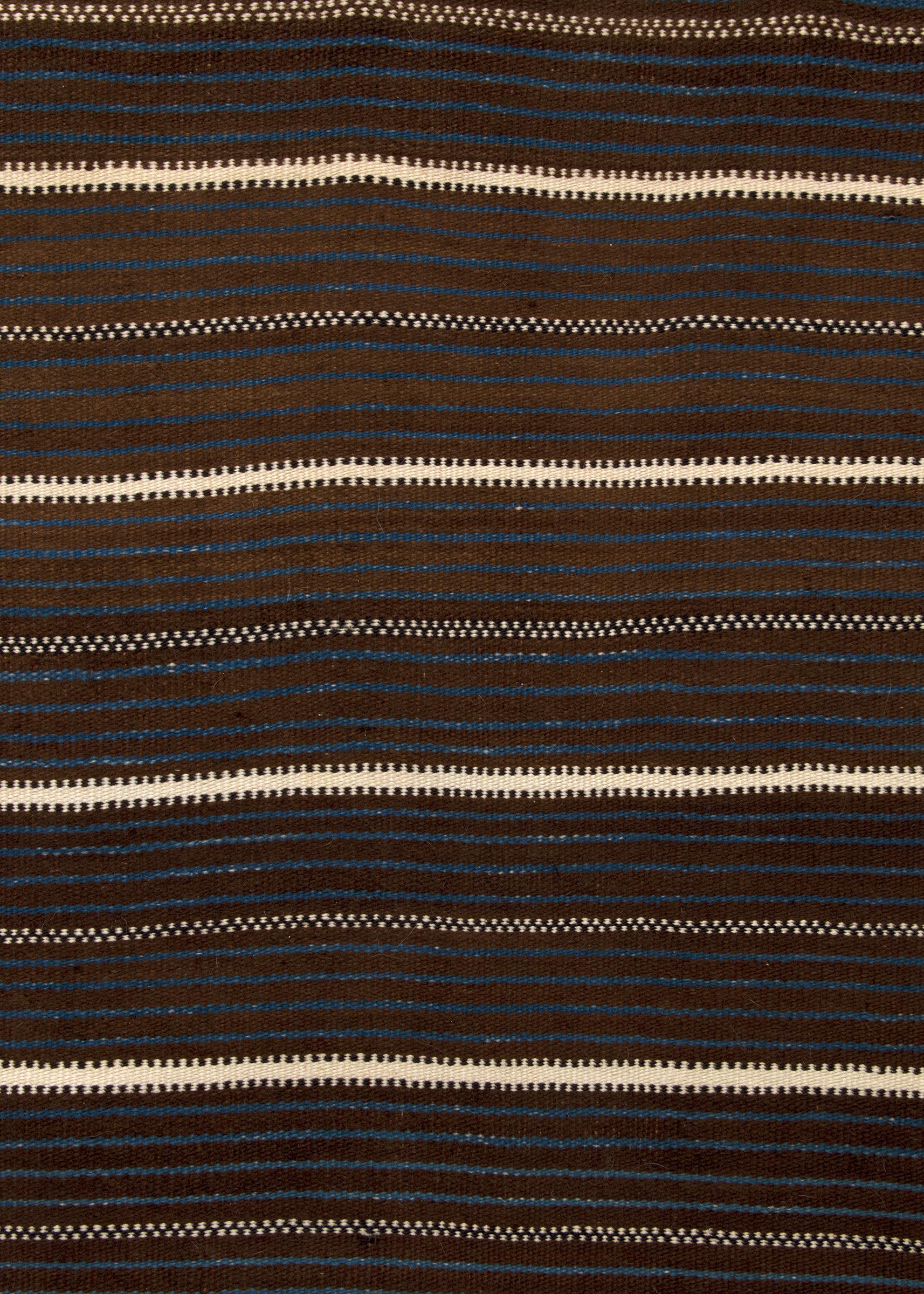 Couverture Zuni ancienne, d'origine amérindienne, au design classique composé de bandes composées dans un motif de style Moki. L'alternance de bandes brunes et indigo est parfois interrompue par des bandes blanches. Laine native filée à la main dans