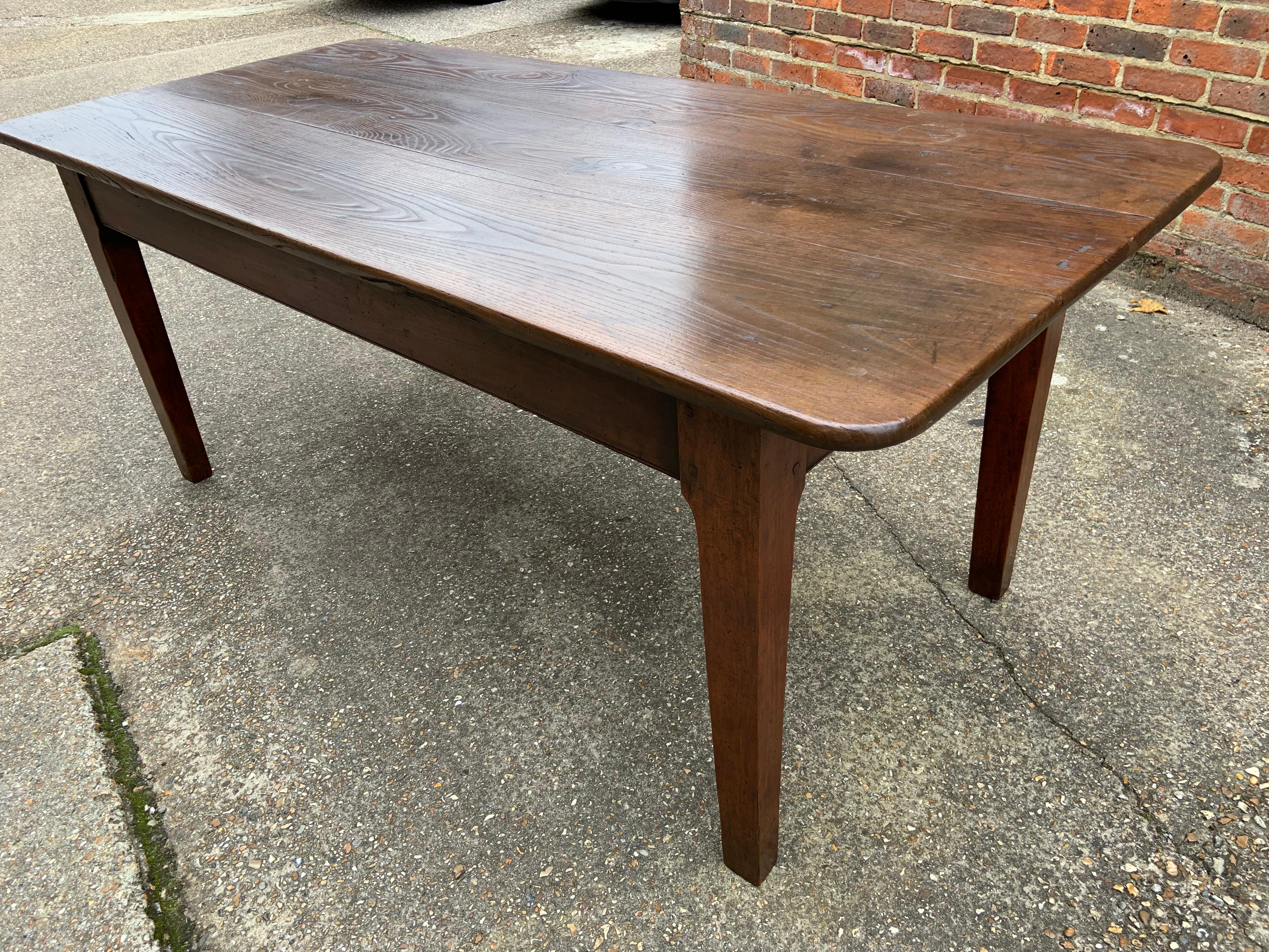 19th century Chestnut farmhouse table with rounded corners and three plank top. The sits on a sturdy base with tapered legs and it has an end drawer.

      