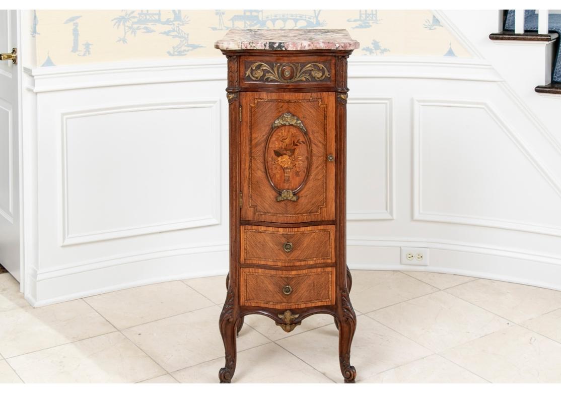 A tall French style cabinet with great color and fine form. The center parquet door with marquetry panel and one shelf inside. Two lower banded parquet drawers and banded parquet sides. Fluted half column supports and pink and black conforming