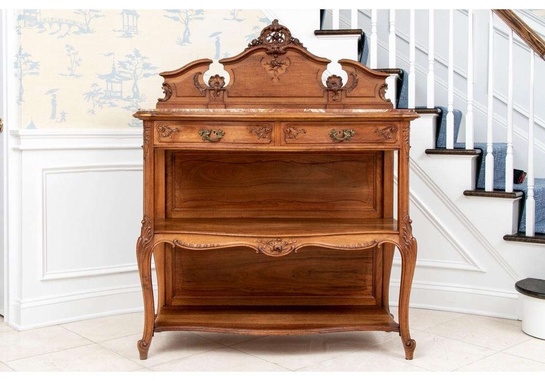 With a carved shaped openwork back splash with shell and floral motifs and a cartouche crest. The shaped top tier with conforming pink and white marble top. Two carved apron drawers having dove-tail construction with brass pulls and key holes and