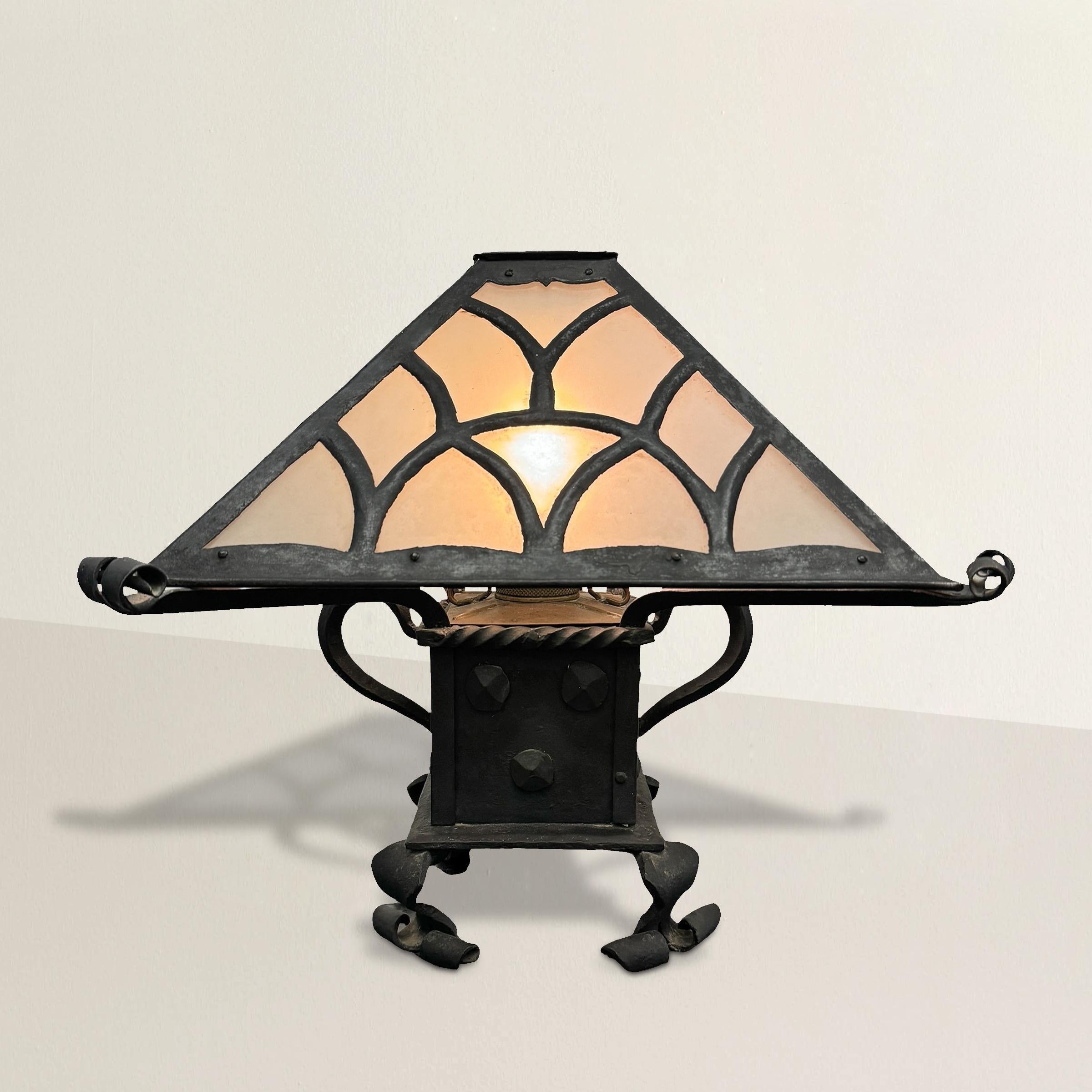 This late 19th/early 20th-century American Arts and Crafts hand-wrought iron oil lamp is an absolute masterpiece of design and craftsmanship. Now electrified for modern convenience, this lamp retains its original beauty and charm while seamlessly
