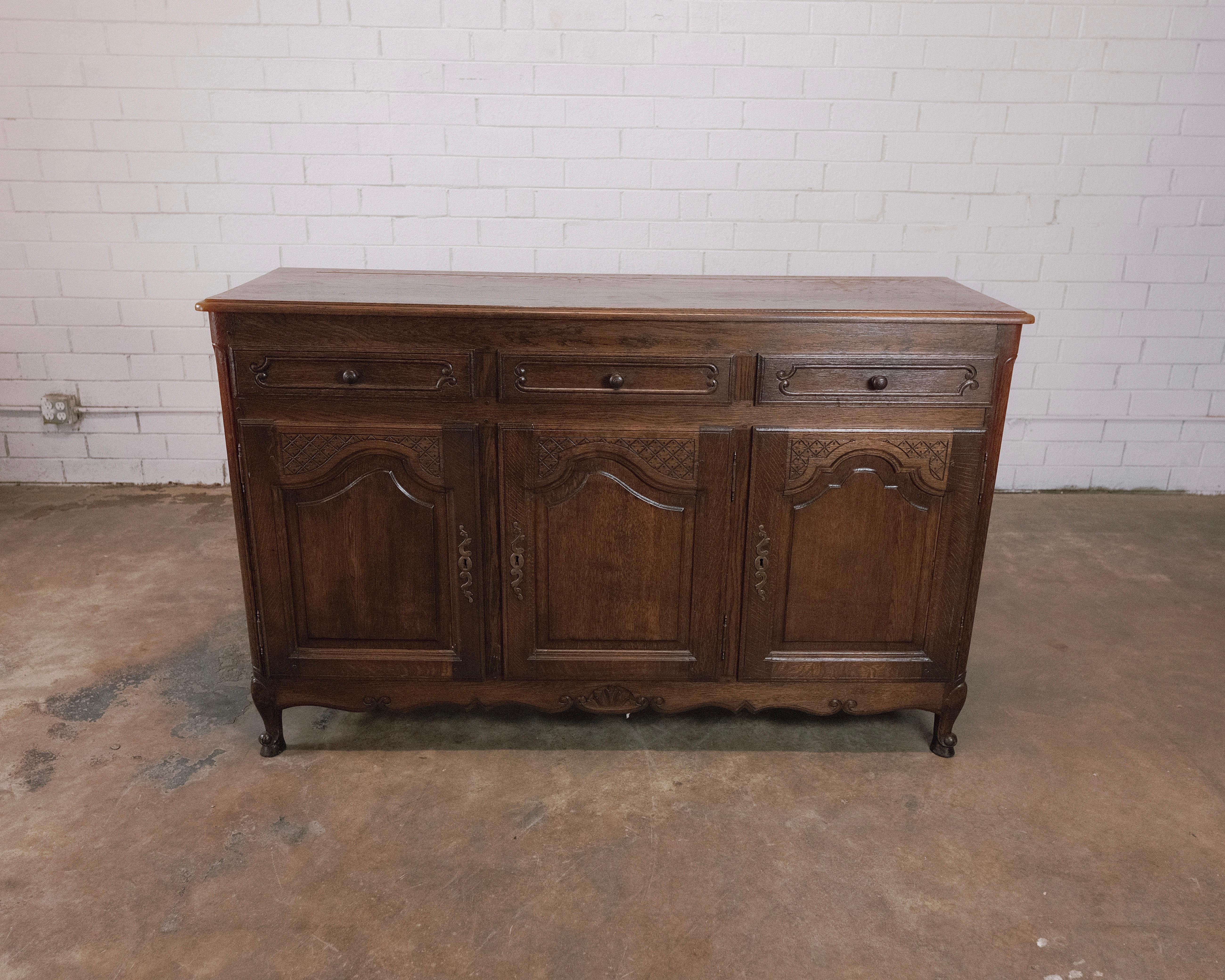 Step back in time to the rustic charm of the Late 19th to Early 20th Century with this antique French Country Sideboard in a rich, dark brown finish, adorned with beautiful brass hardware. This captivating piece encapsulates the essence of a bygone