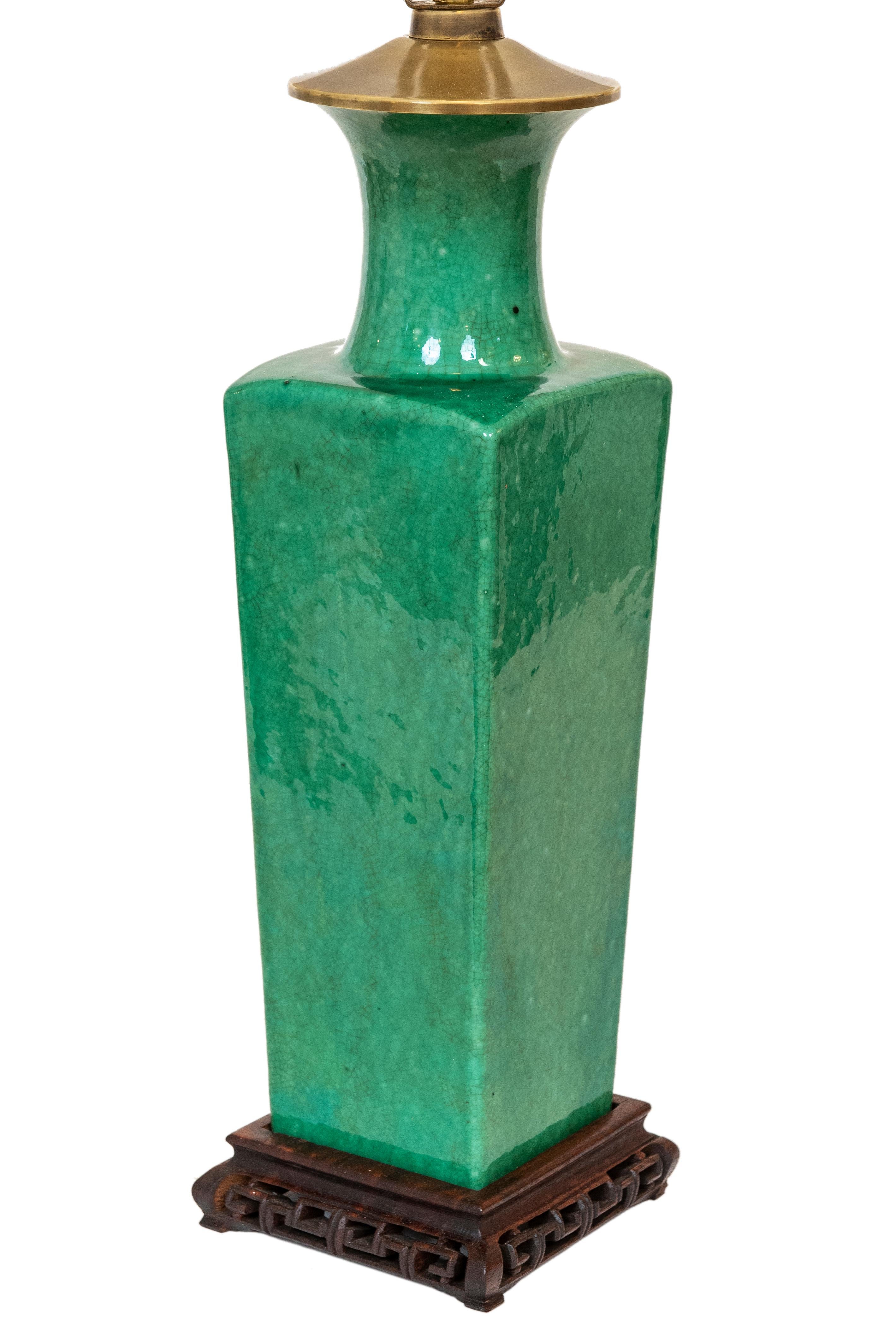 This vibrant and stunning apple/mint green urn shaped lamp has a beautiful crackle glazed finish and is mounted on a carved wood decorative base. The lamp has been cleaned and rewired with new socket and cord. It is fitted with a white linen style