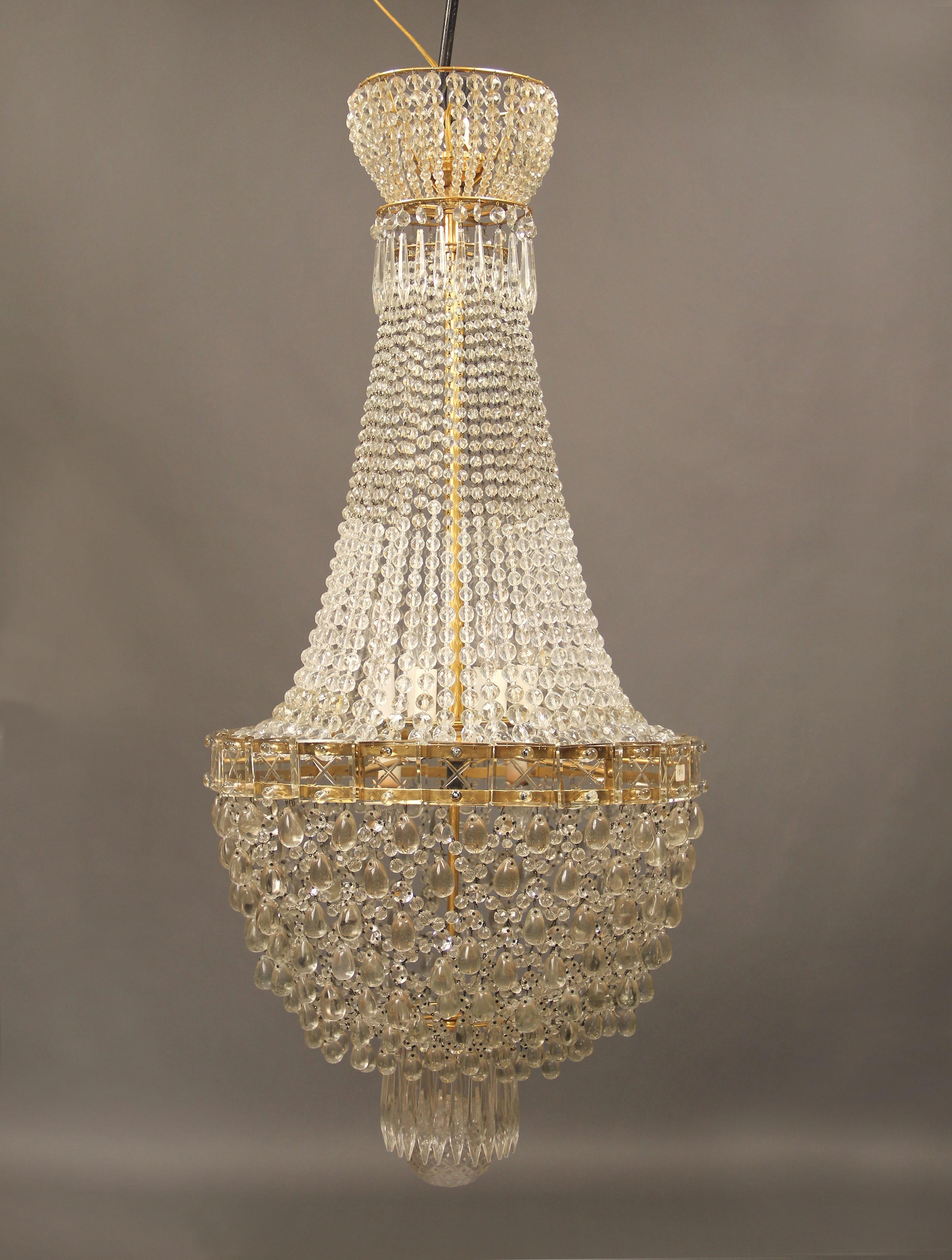 Late 19th/Early 20th Century Gilt Bronze and Beaded Eight Light Basket Chandelier

The beaded crown with a gilt bronze rim, beaded strings run down to a fine etched square crystal frame, the basket with intertwined large crystal bulbs and beads,