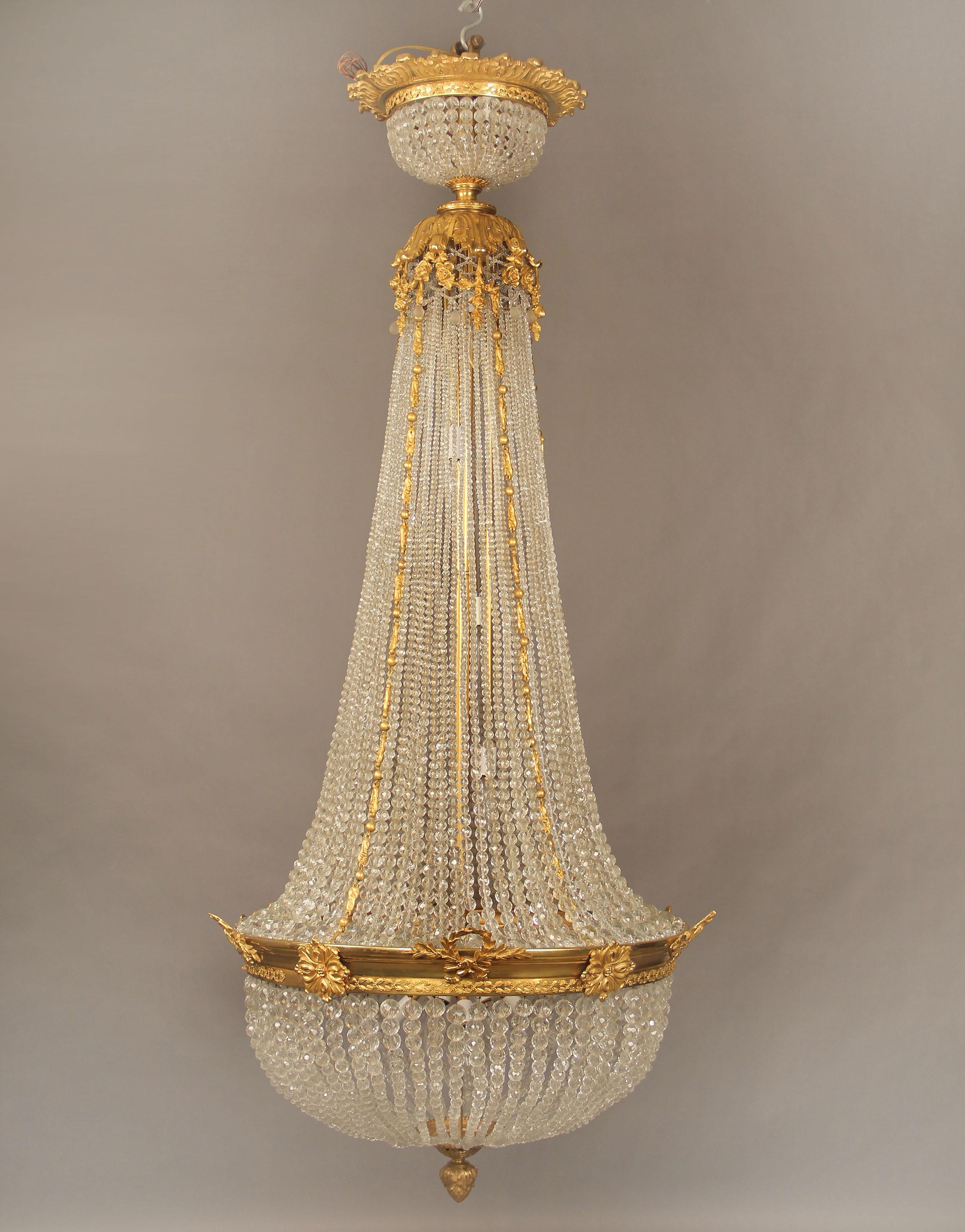 A Lovely Late 19th/Early 20th Century Gilt Bronze and Beaded Twenty Light Basket Chandelier

The crown designed with bronze roses and flowers, the flowing crystal beads connected to a bronze conforming entwined garland frieze with wreaths, an acorn