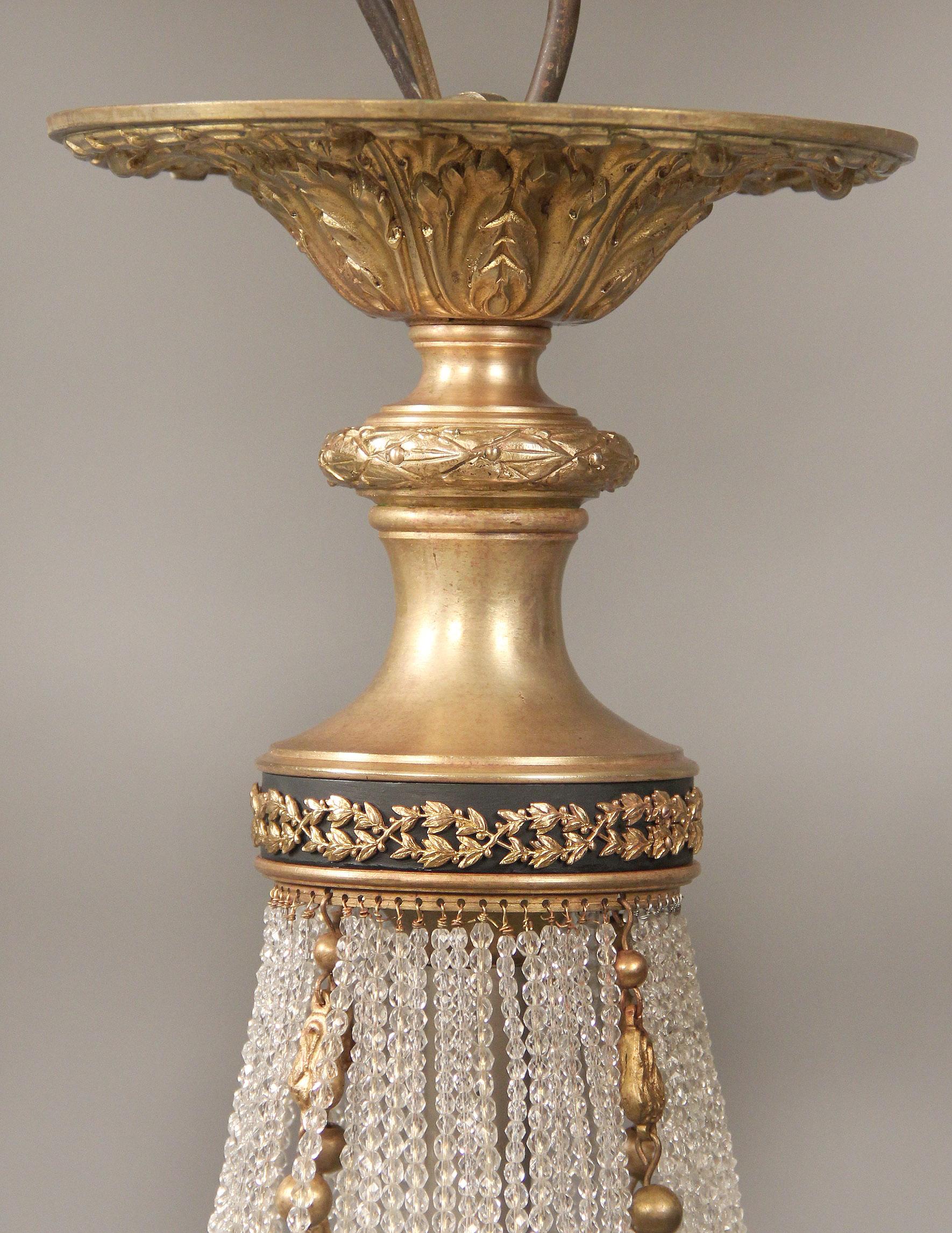Late 19th-early 20th century gilt bronze beaded basket twelve-light chandelier.

The upper and lower part of the cage connected by ribbed bronze straps, four perimeter lights with frosted rose shades and eight tiered interior lights.