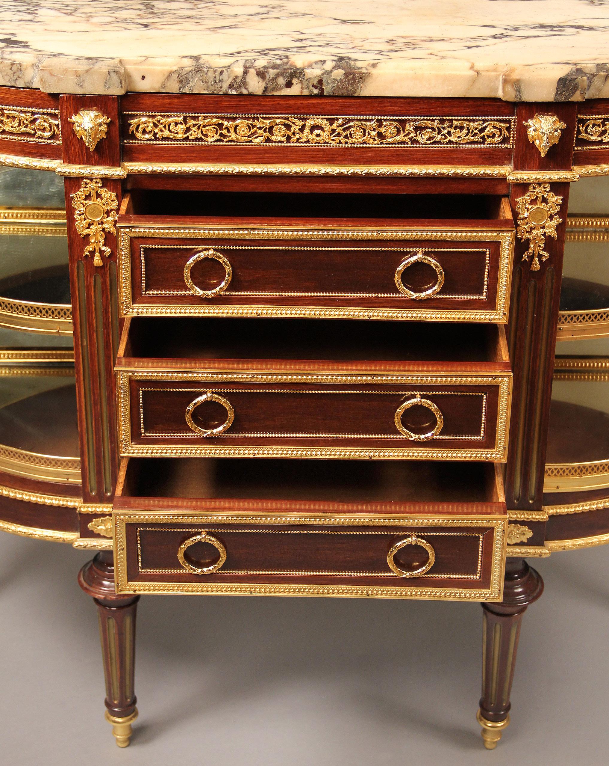 A nice late 19th-early 20th century gilt bronze mounted Louis XVI style cabinet or server

The demilune marble top above bronze Vitruvian scrolled design and four ram heads with three central drawers, the case corners with two mirrored galleried